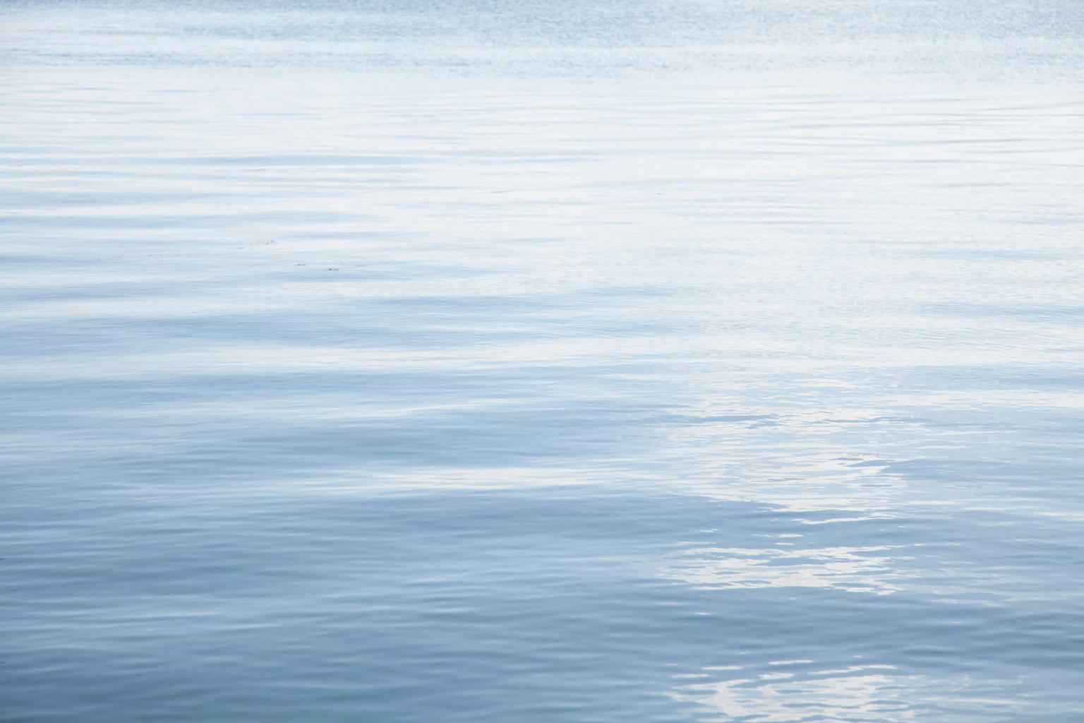 Surface d'eau bleue calme avec des reflets
