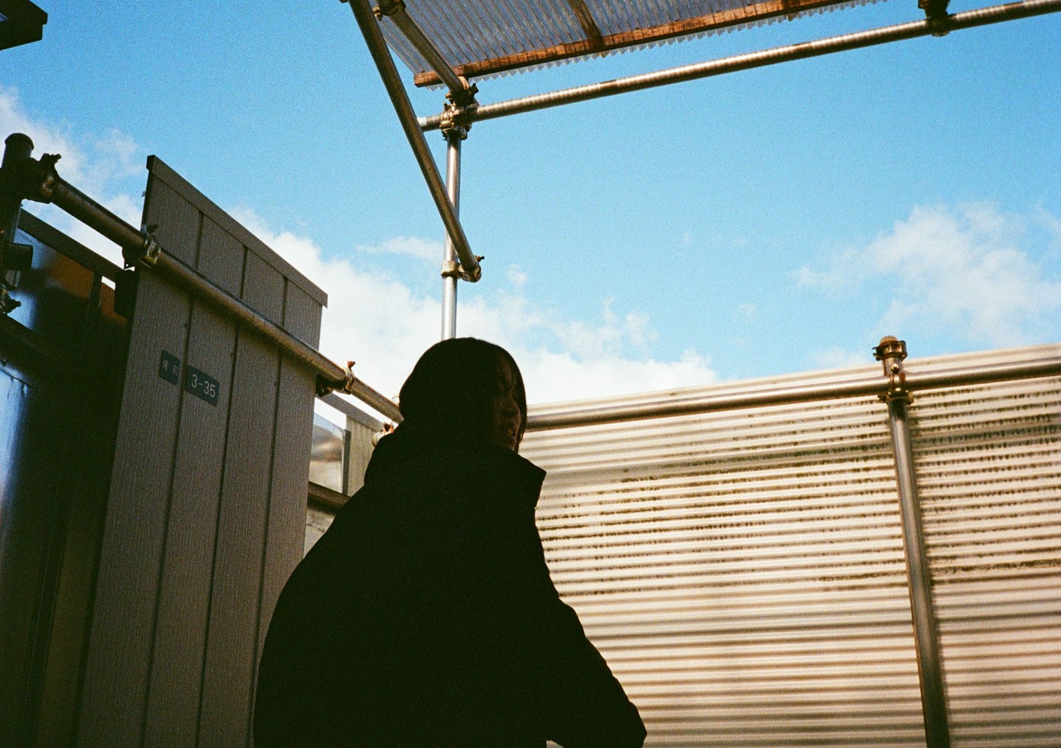 青空の下でシルエットの人物が立っている構図