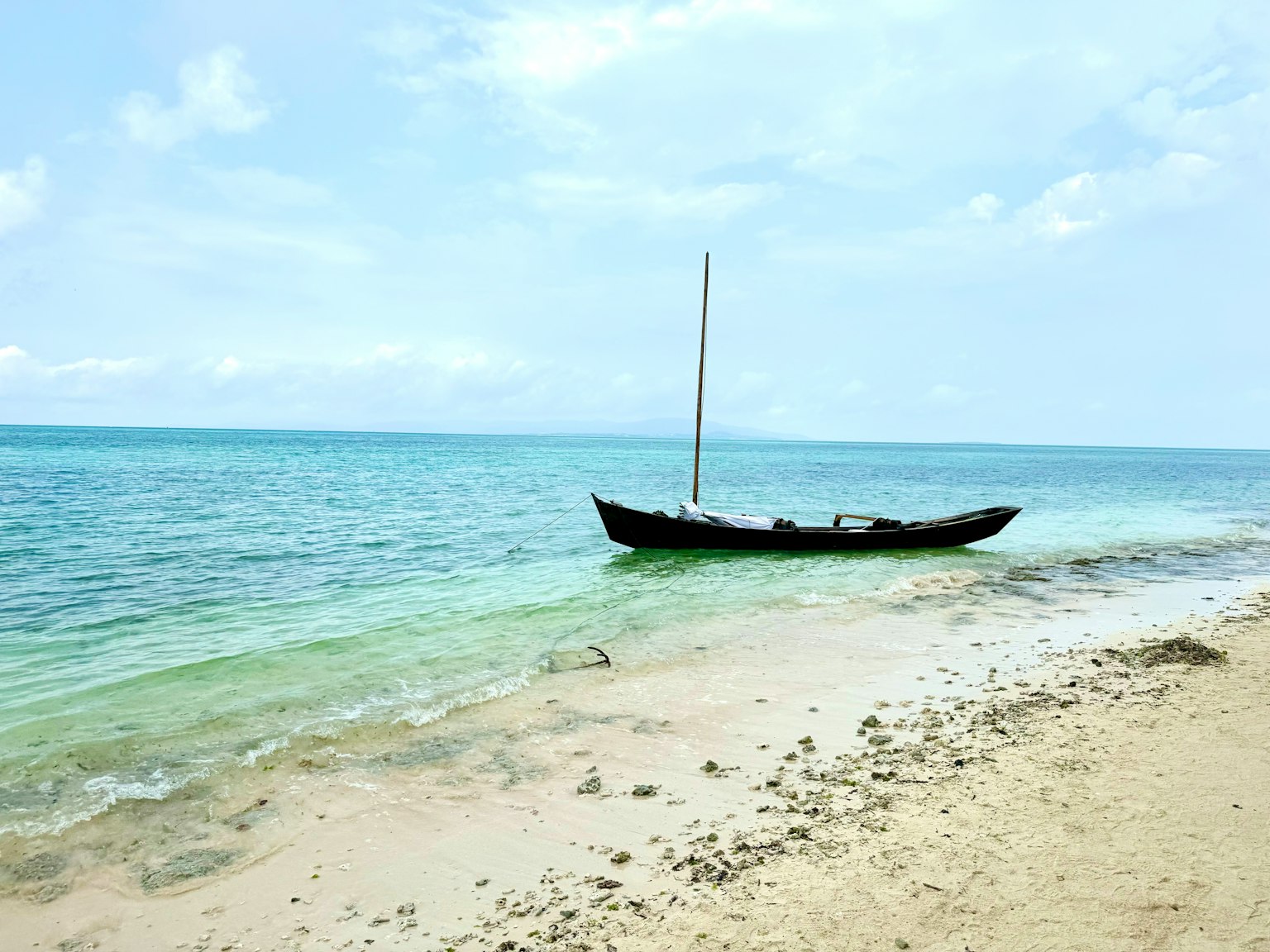 Ein kleines Boot liegt an einem ruhigen Strand mit klarem blauem Wasser