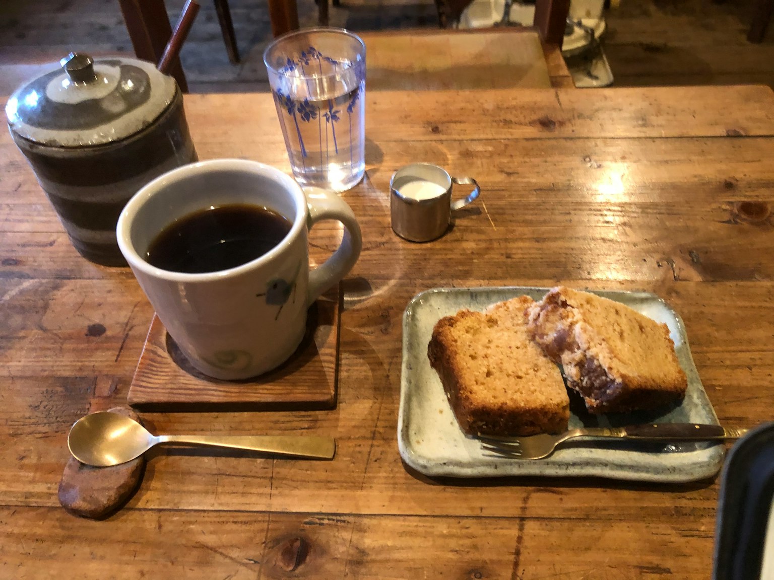 Una tazza di caffè nero con una fetta di torta su un tavolo di legno rustico