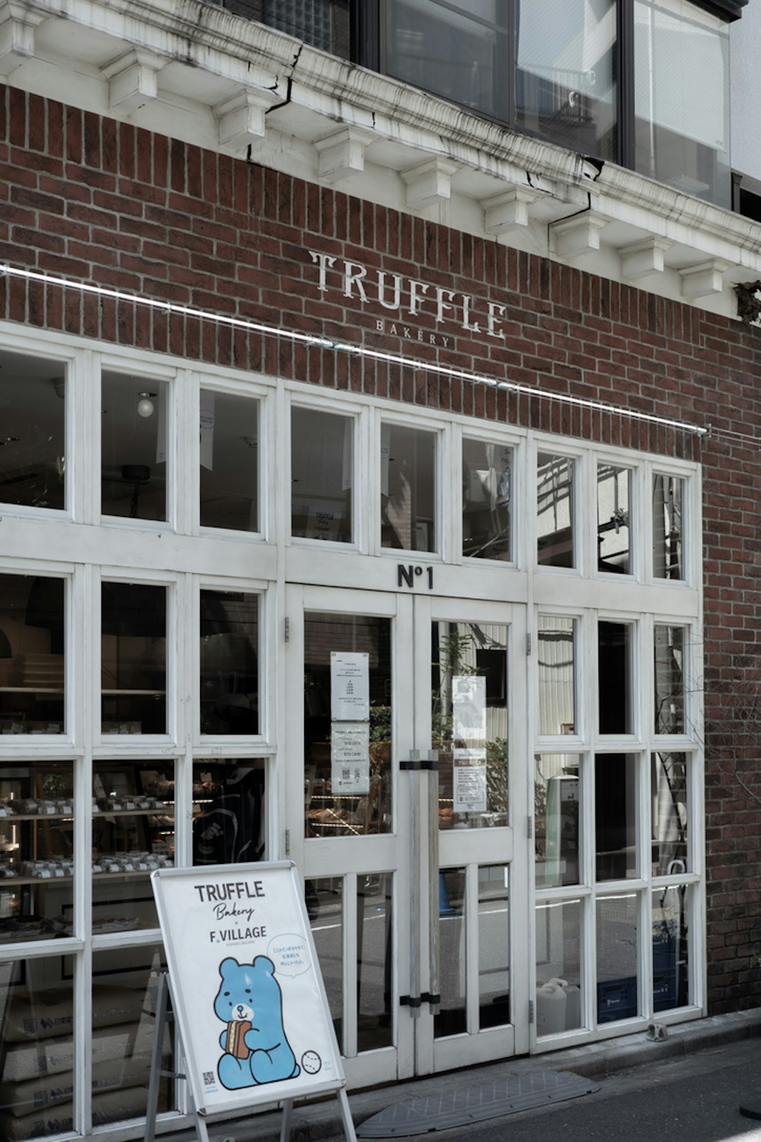 ภายนอกของร้านที่ชื่อ TRUFFLE มีหน้าต่างสว่างและประตูสีขาว