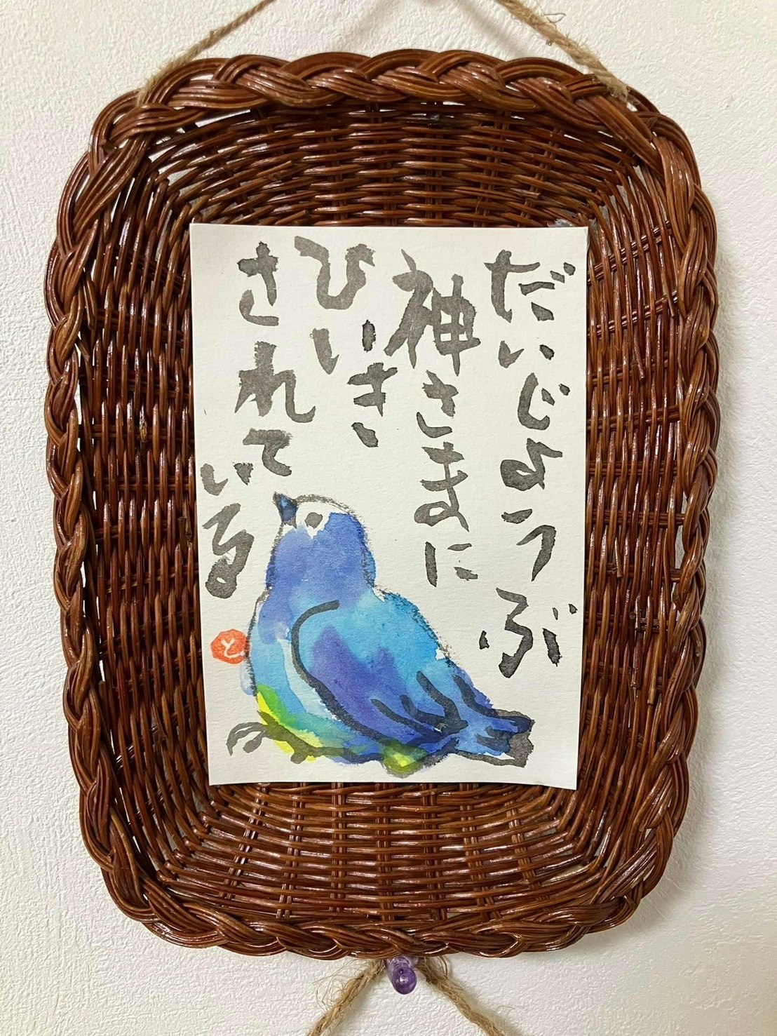 Blue bird illustration displayed in a woven rattan wall hanging