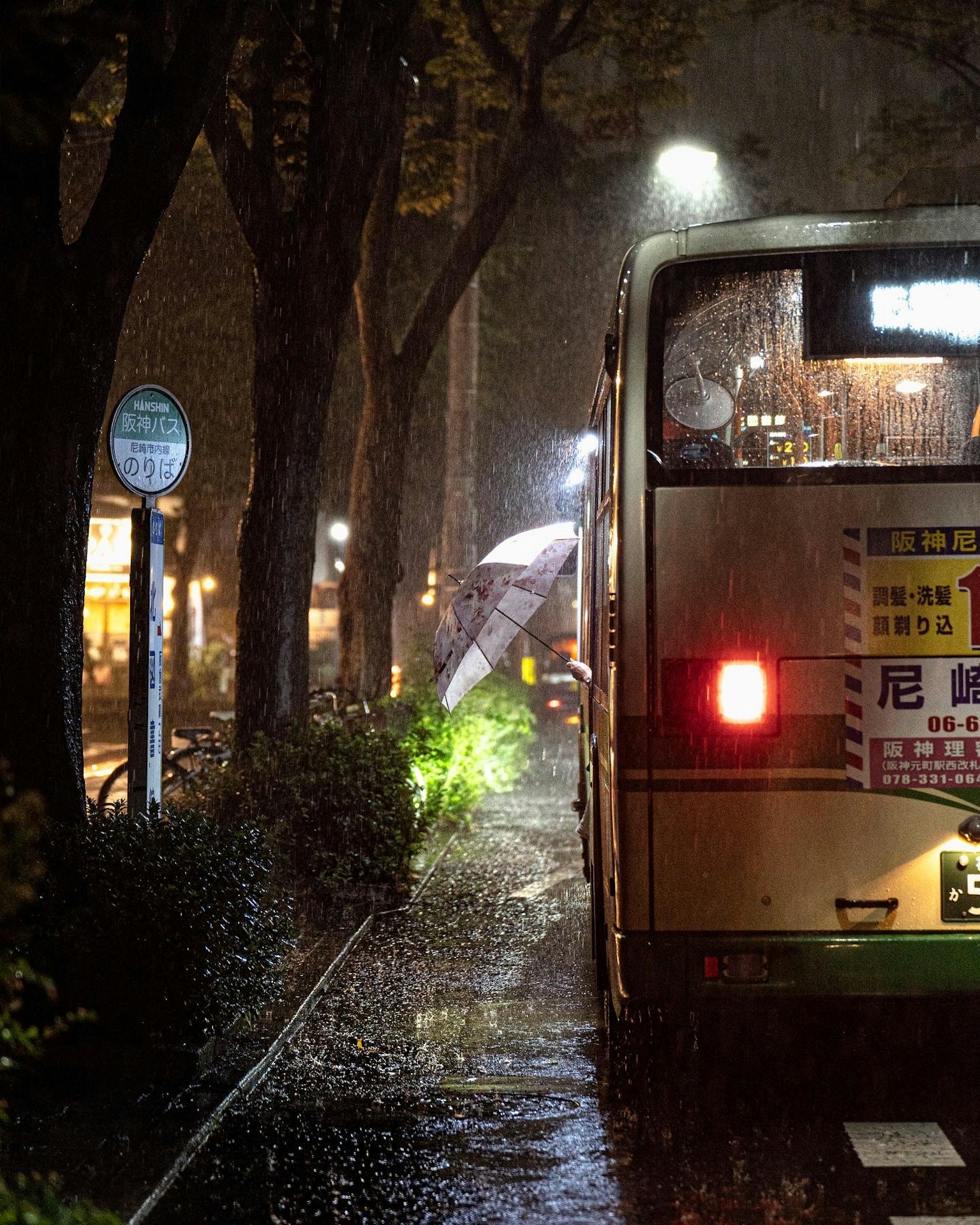 在雨中停著的公車和撐著傘的人
