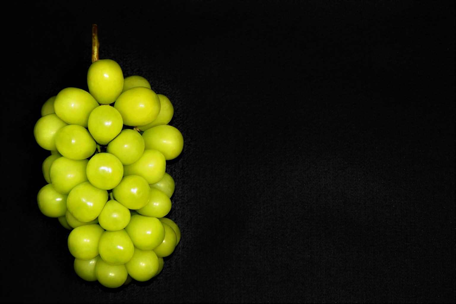 A cluster of green grapes against a black background