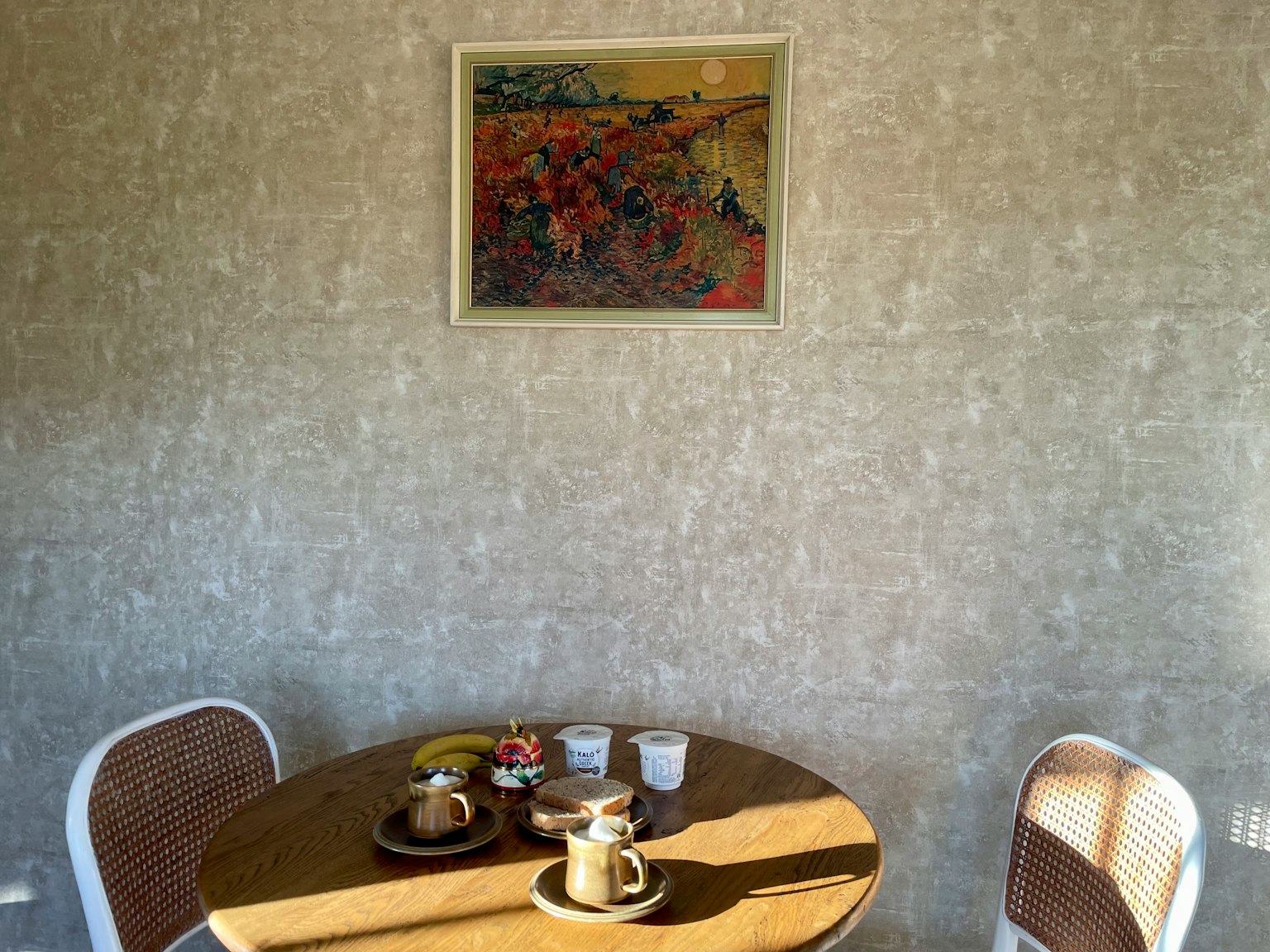 Un rincón acogedor con una mesa preparada para café y dulces con una pintura colorida en la pared