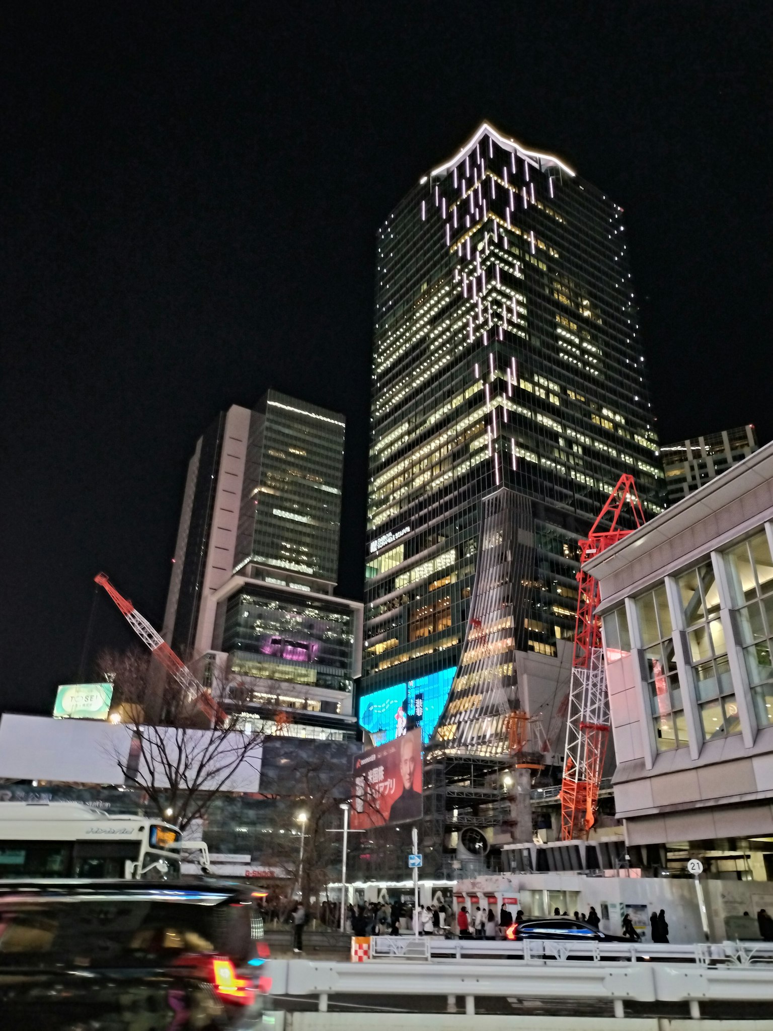 Paisaje urbano nocturno con rascacielos iluminados y grúas de construcción