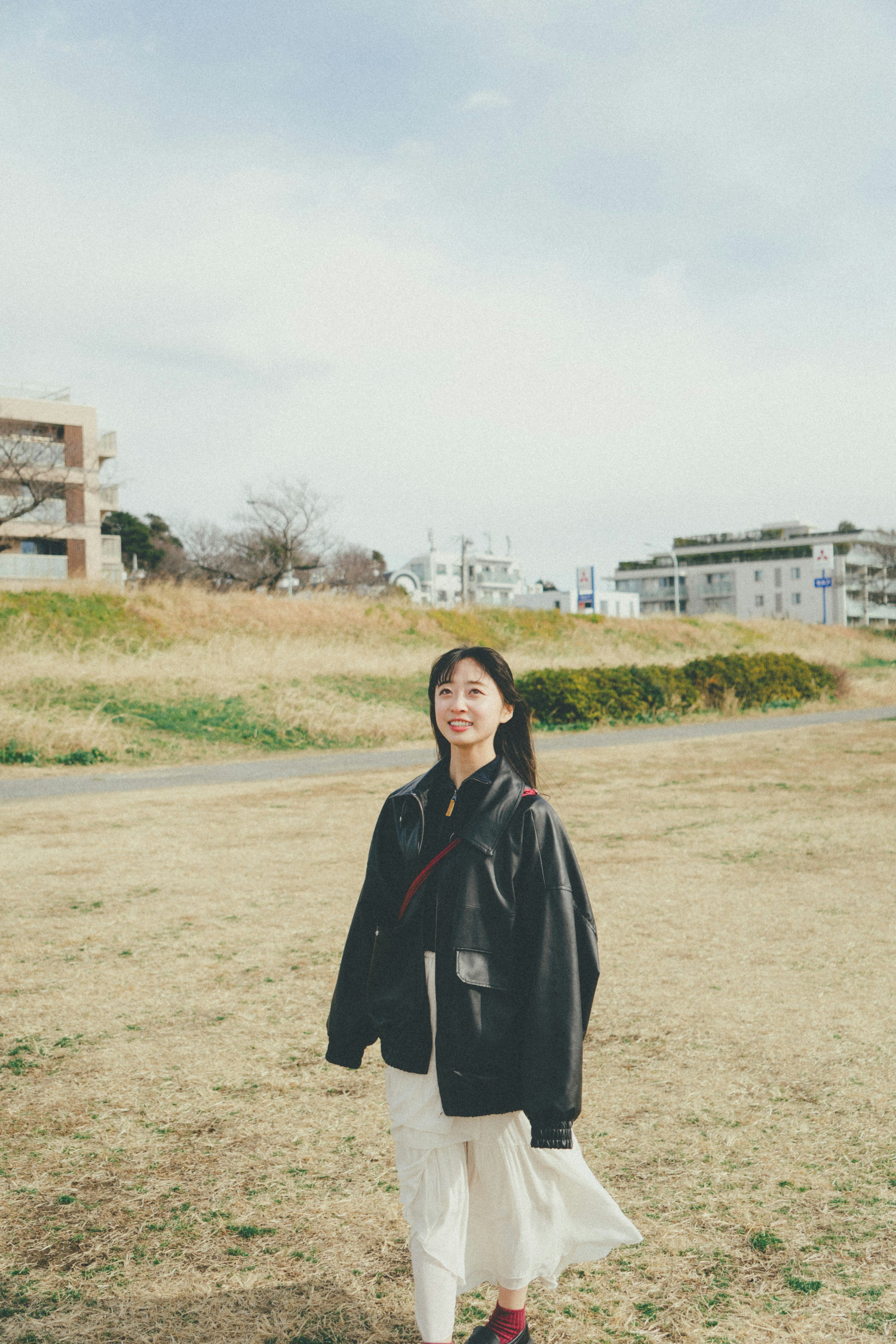 穿黑色外套的女性站在草地公園裡