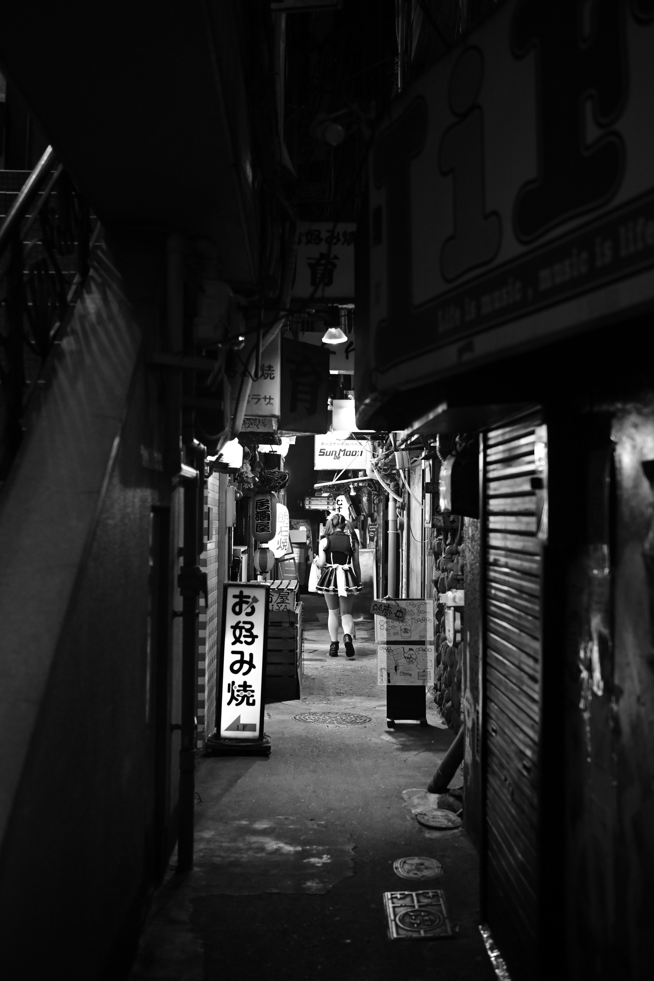 ruelle nocturne avec des boutiques alignées jusqu’au fond