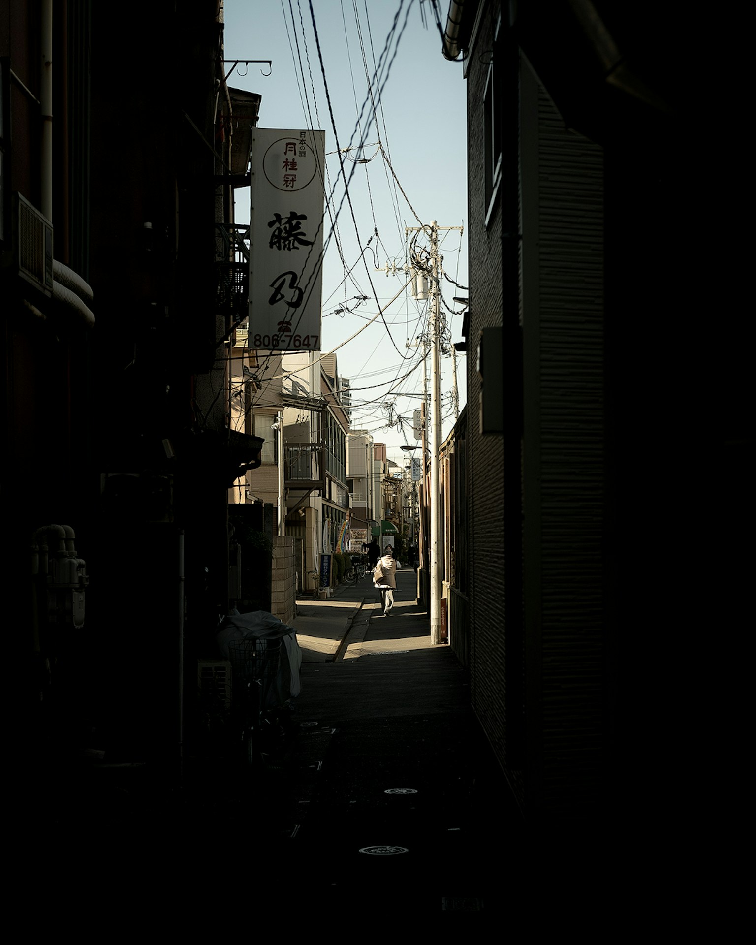 Cortile stretto con la silhouette di una persona e linee elettriche