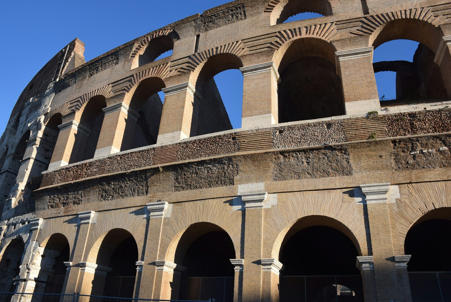 Detailed view of the side of the Colosseum in Rome featuring ancient arches and stone structure