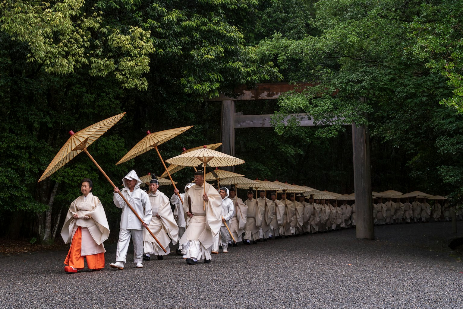 흰색 의상을 입은 사람들이 우산을 들고 행진하는 모습