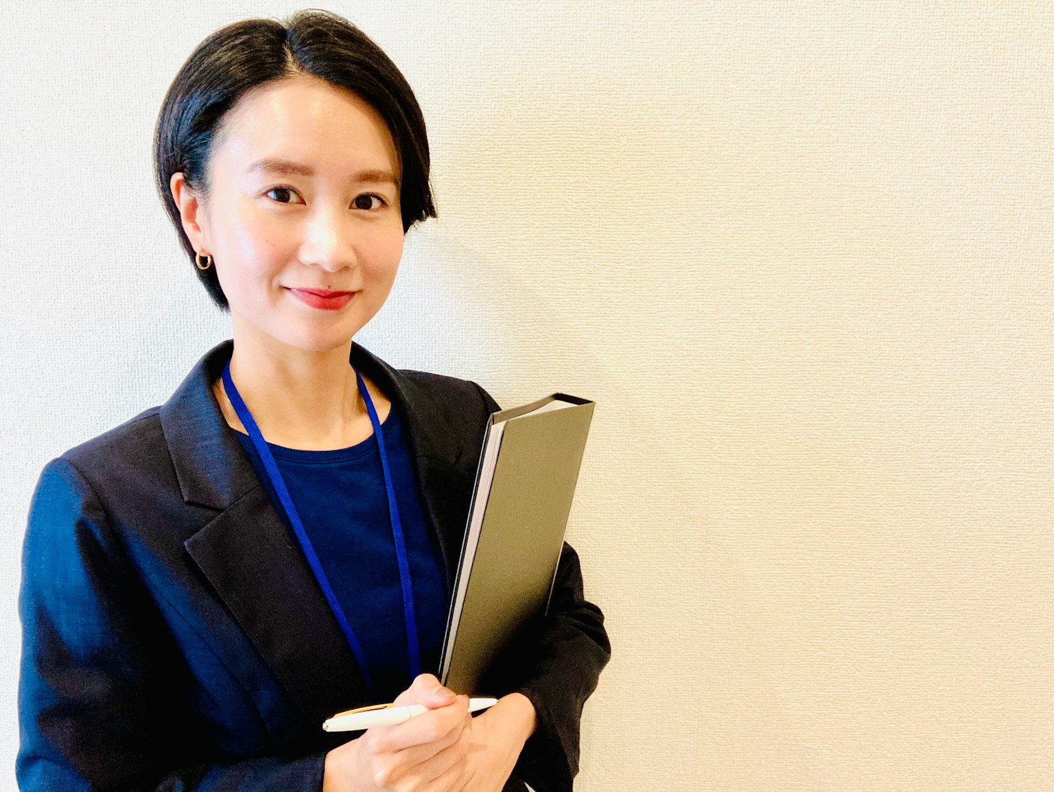 穿著商務套裝的女性手持筆記本微笑