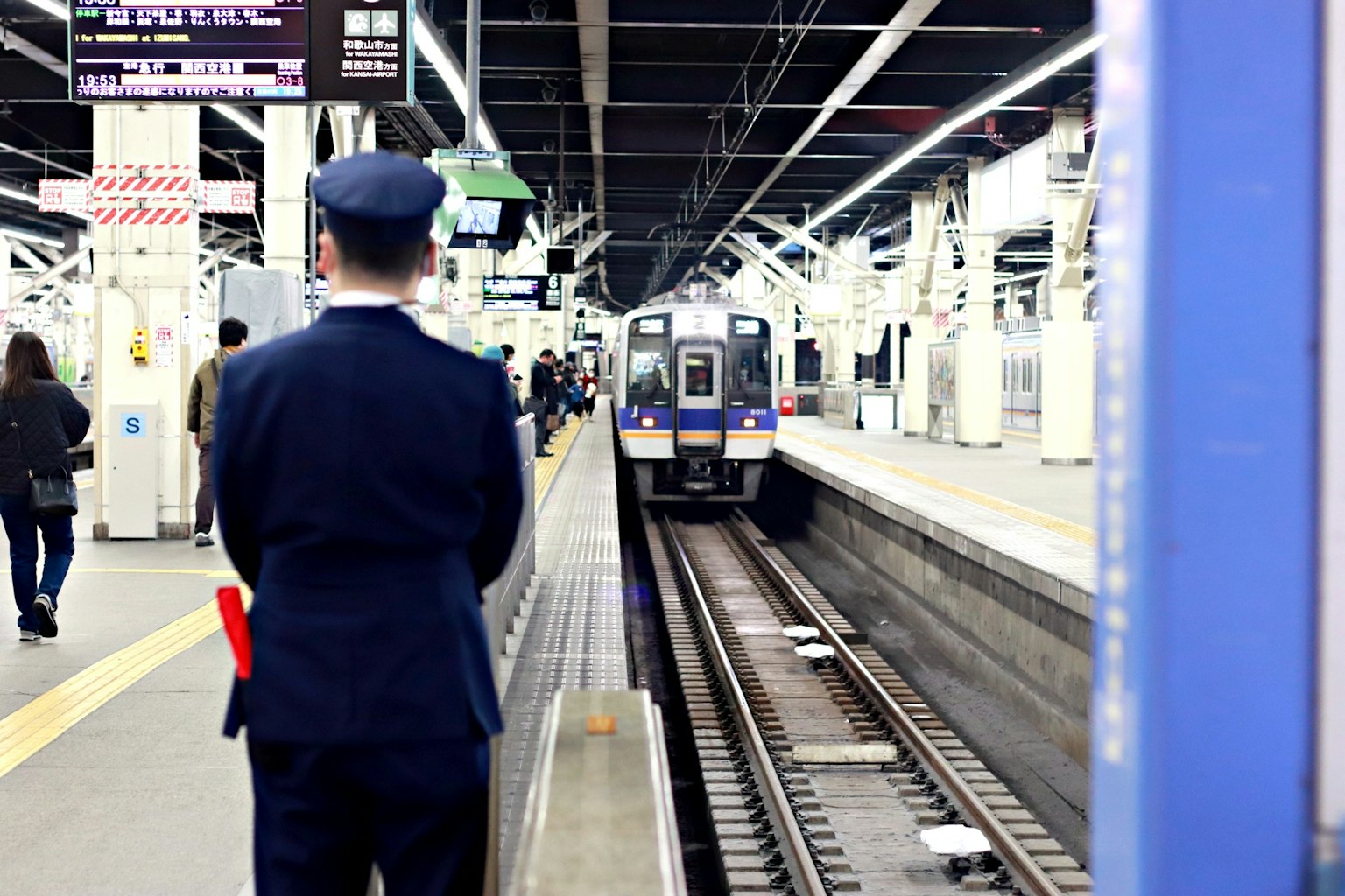 ตำรวจบนชานชาลารอรถไฟพร้อมผู้โดยสารรอบข้าง
