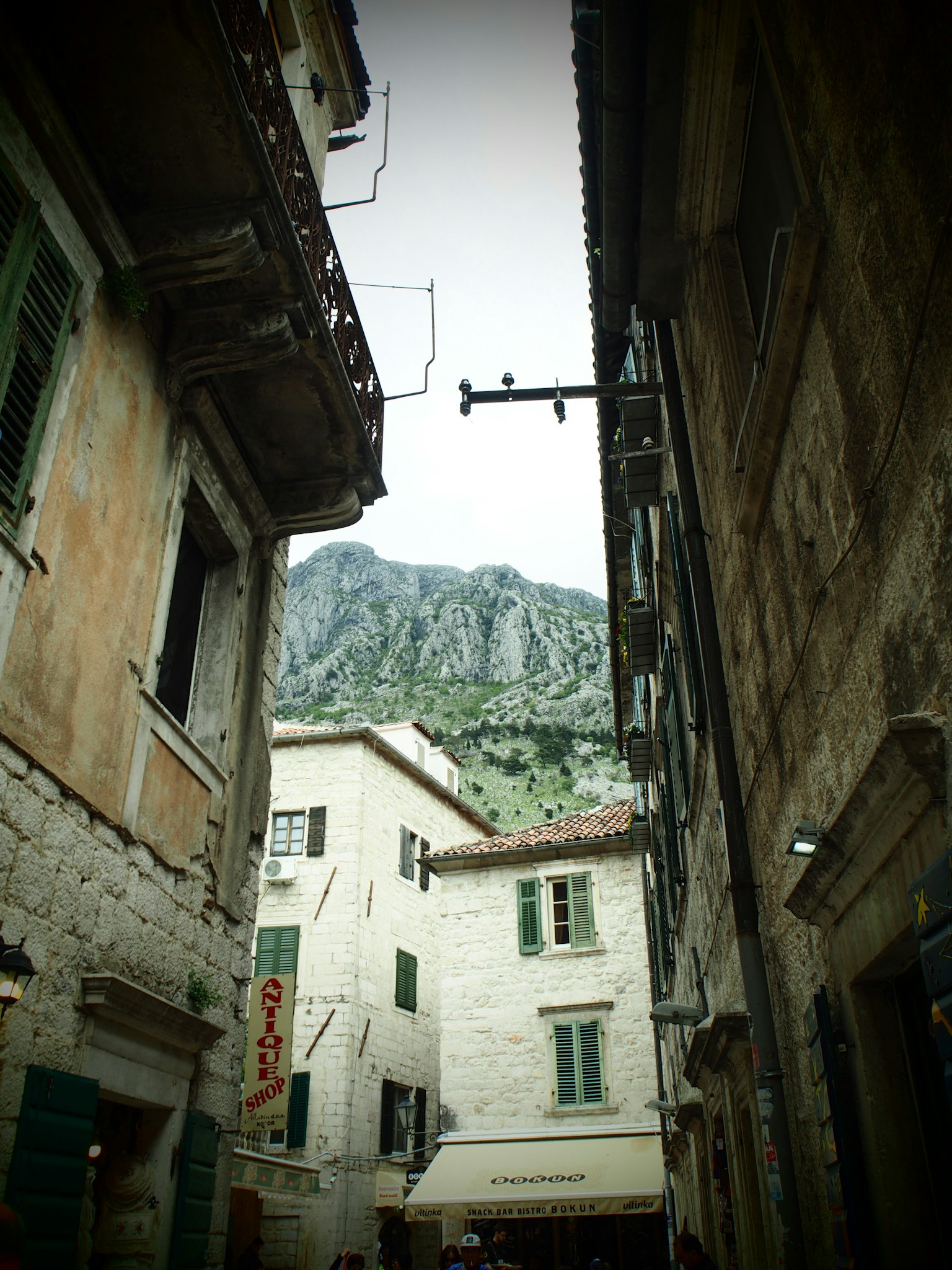Vicolo stretto fiancheggiato da vecchi edifici con vista sulla montagna