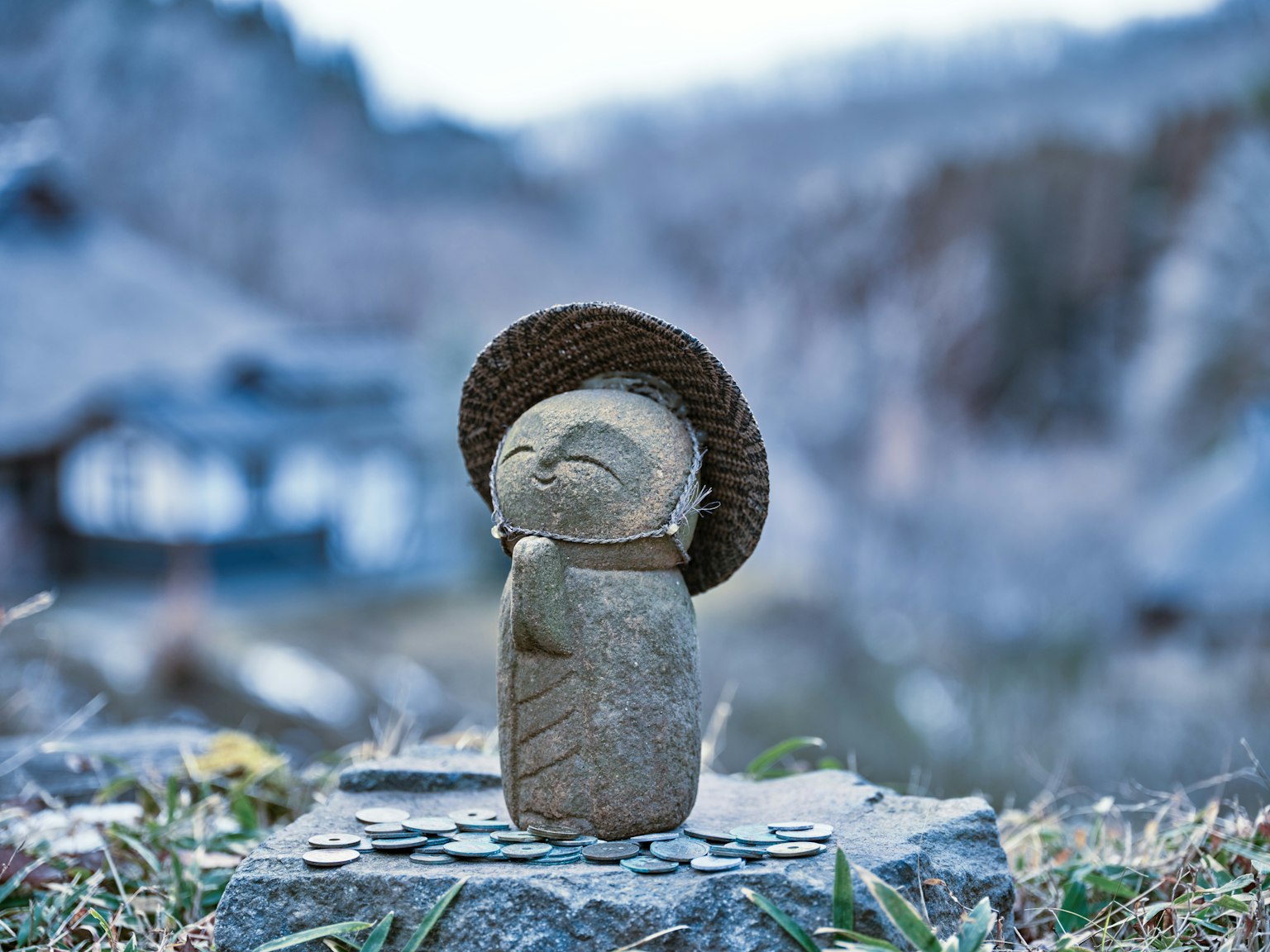 Una figura de piedra con un sombrero y sonriendo en un fondo escénico