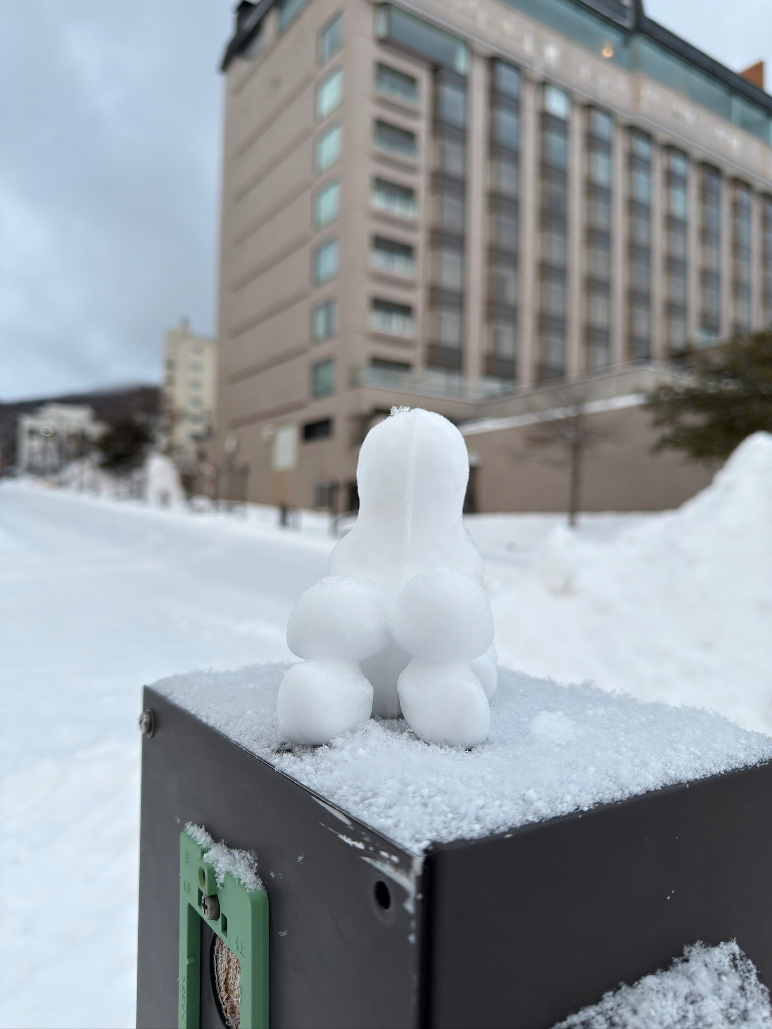 雪の積もったホテルの屋外ベンチに座る雪だるま