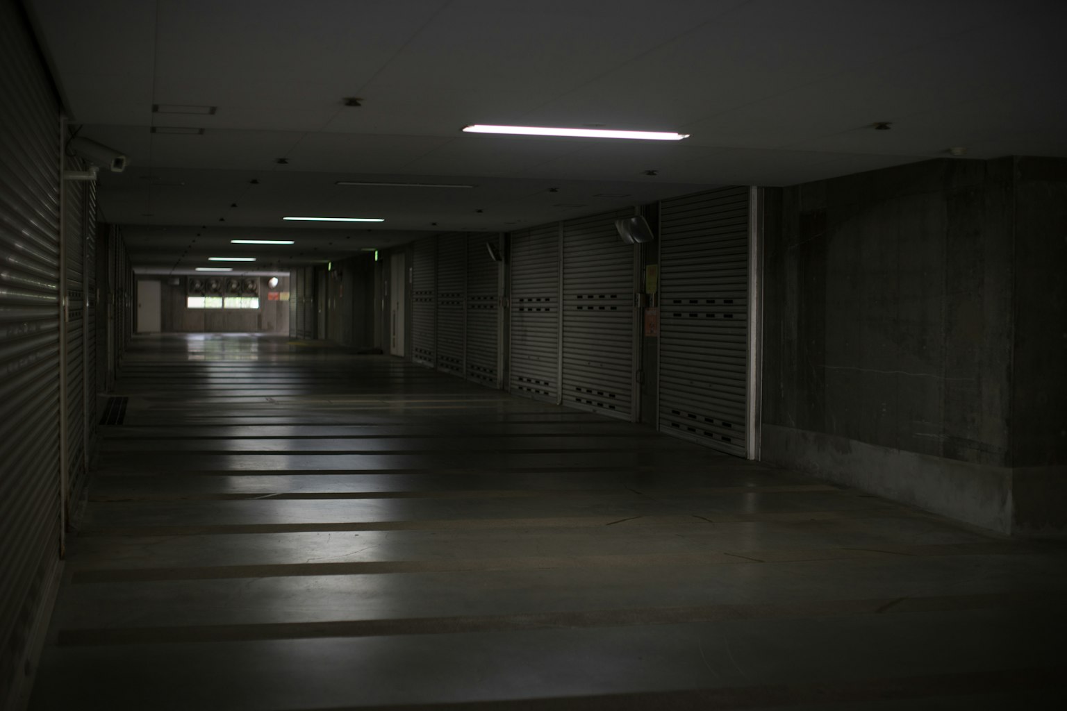 Largo corredor de un pasaje subterráneo débilmente iluminado con suelo liso