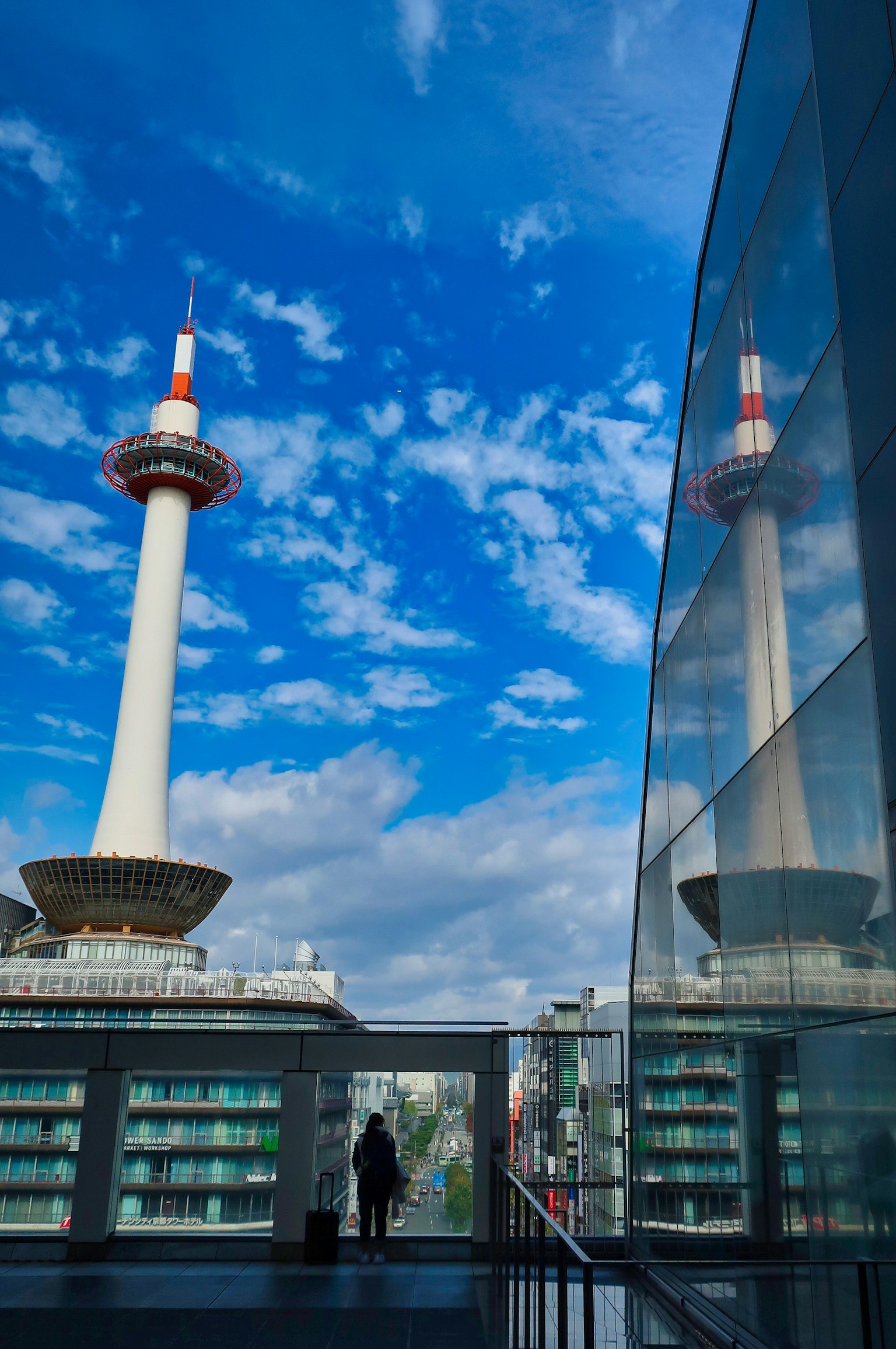 青空の下にある高いタワーとその反射を持つ現代的な建物