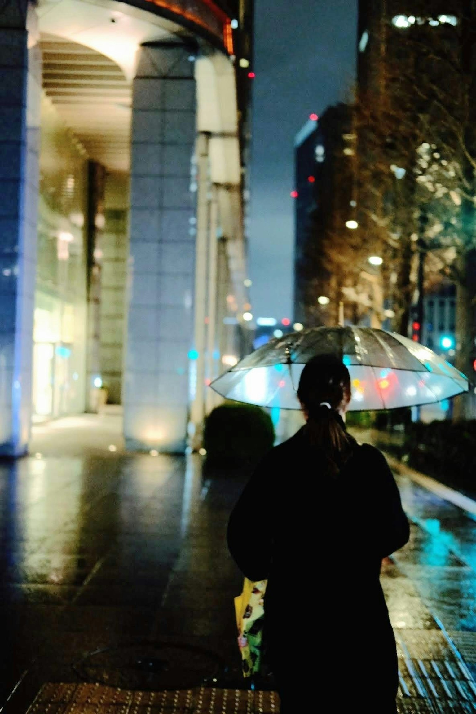 Eine Person mit einem Regenschirm in einer nächtlichen Stadtlandschaft