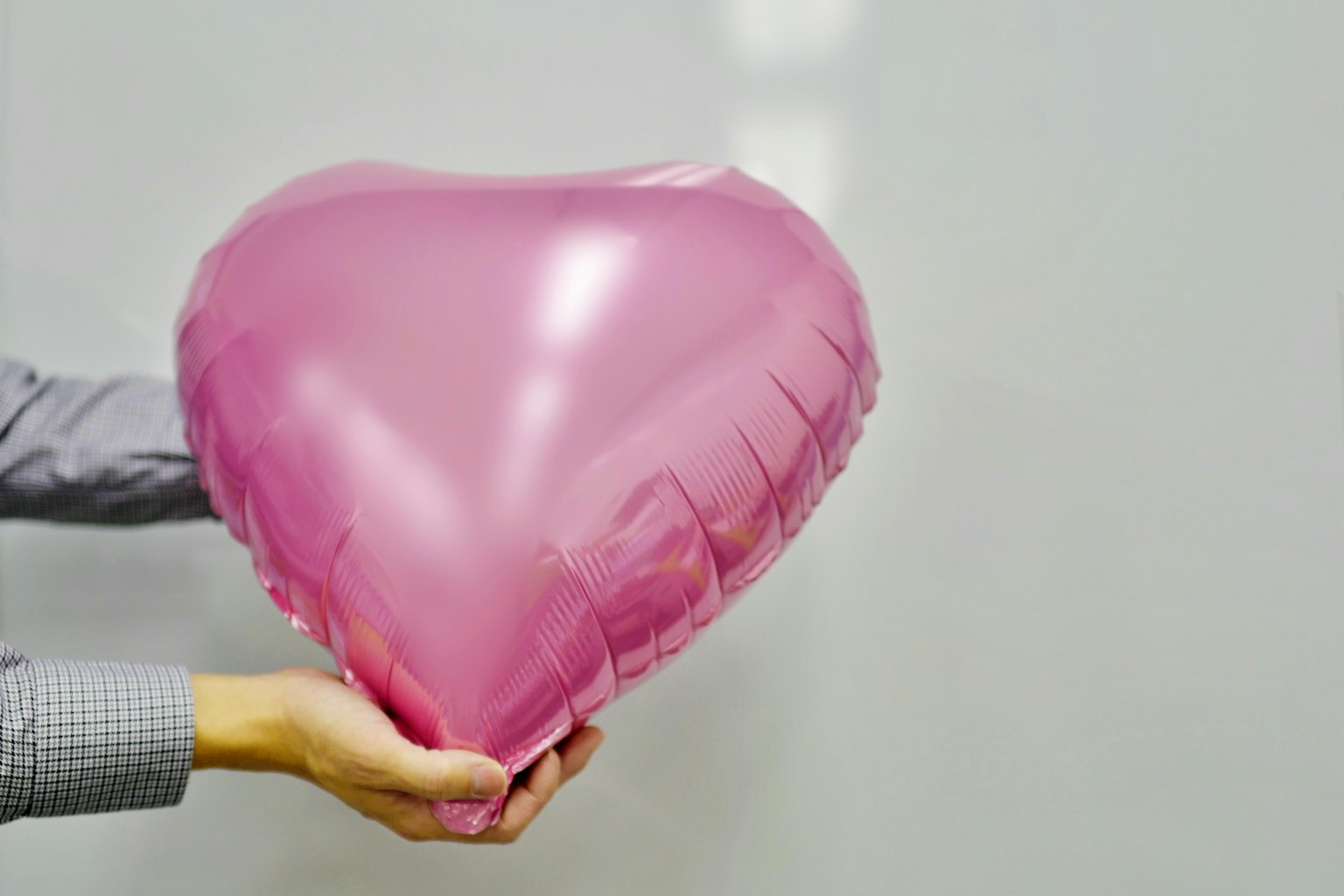 Ein rosa Herzballon, der in Händen gehalten wird