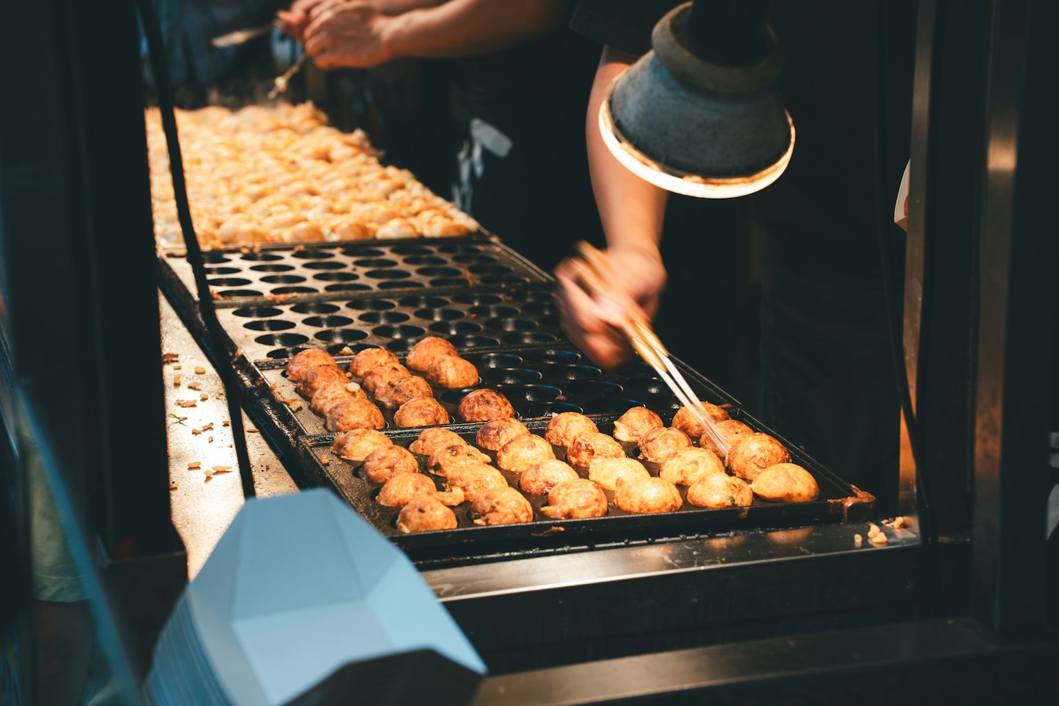 Un venditore che prepara takoyaki su una griglia