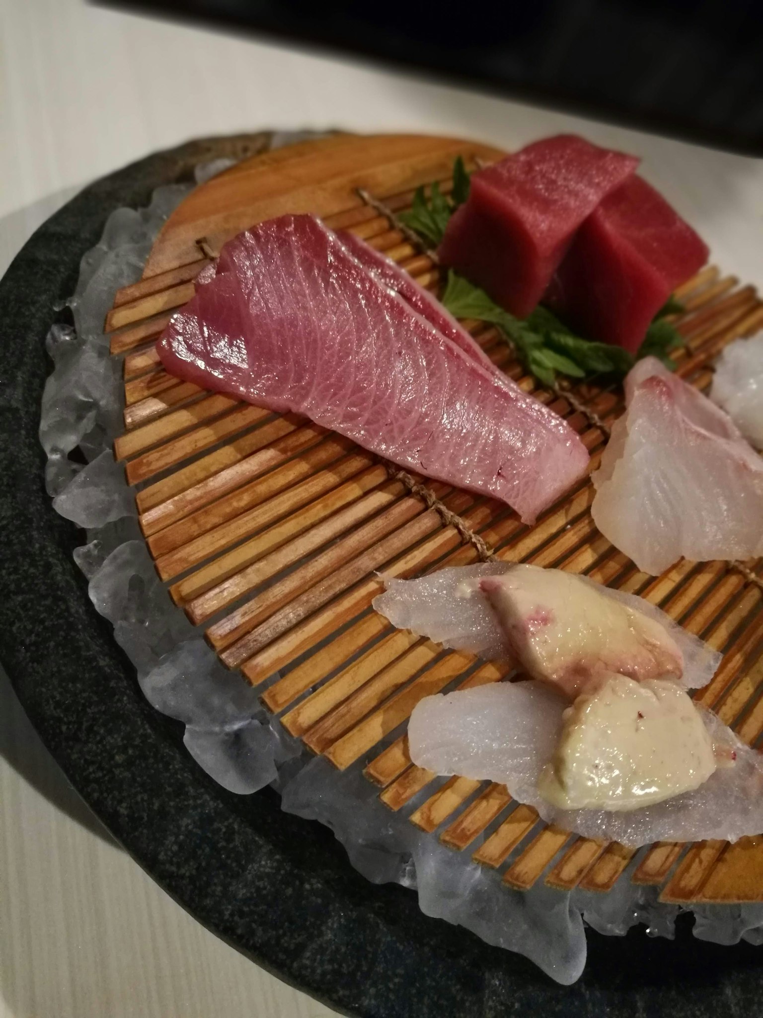 Piring sashimi segar yang disusun di atas papan kayu di atas es