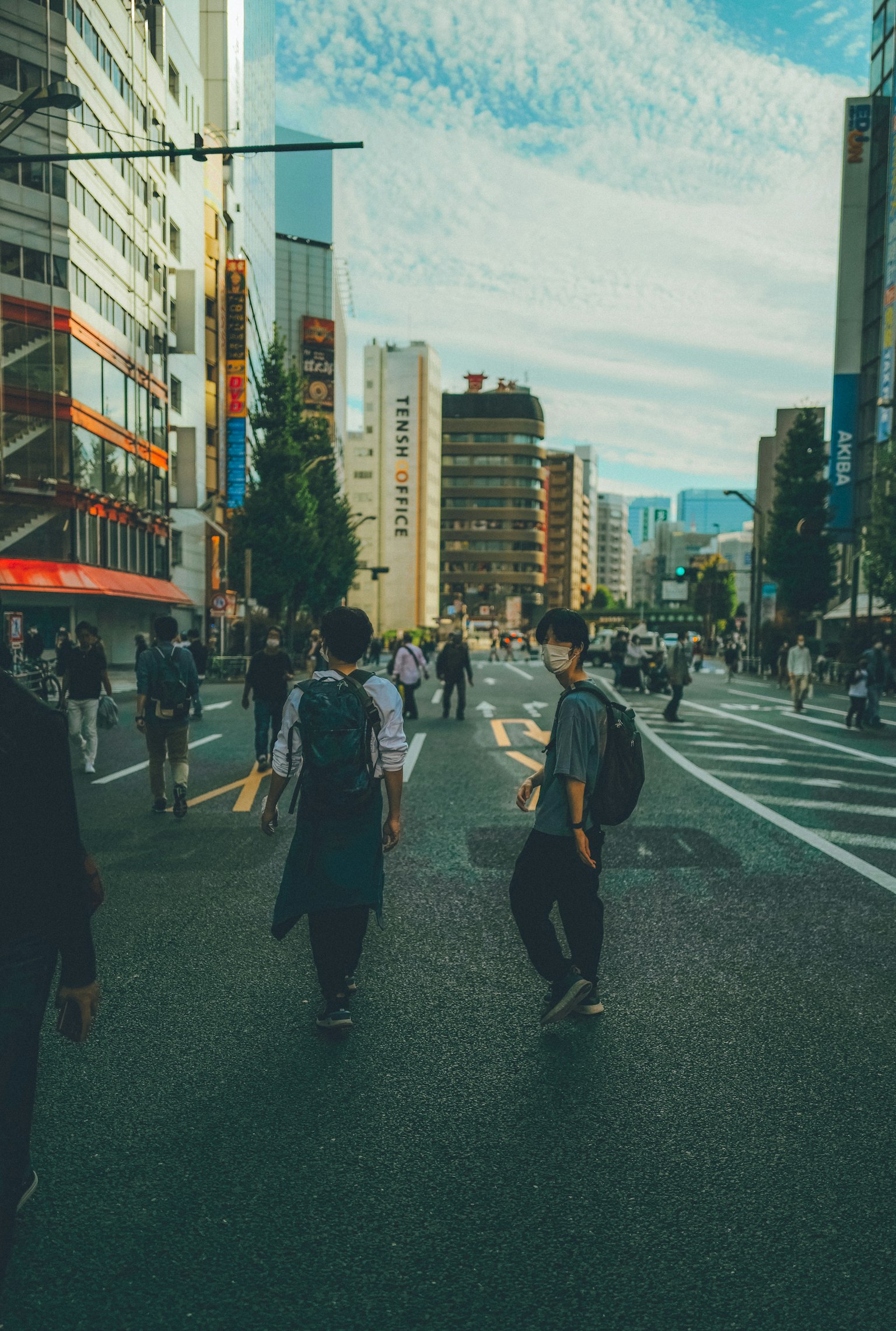 Persone che camminano in una strada di città con edifici e cielo blu
