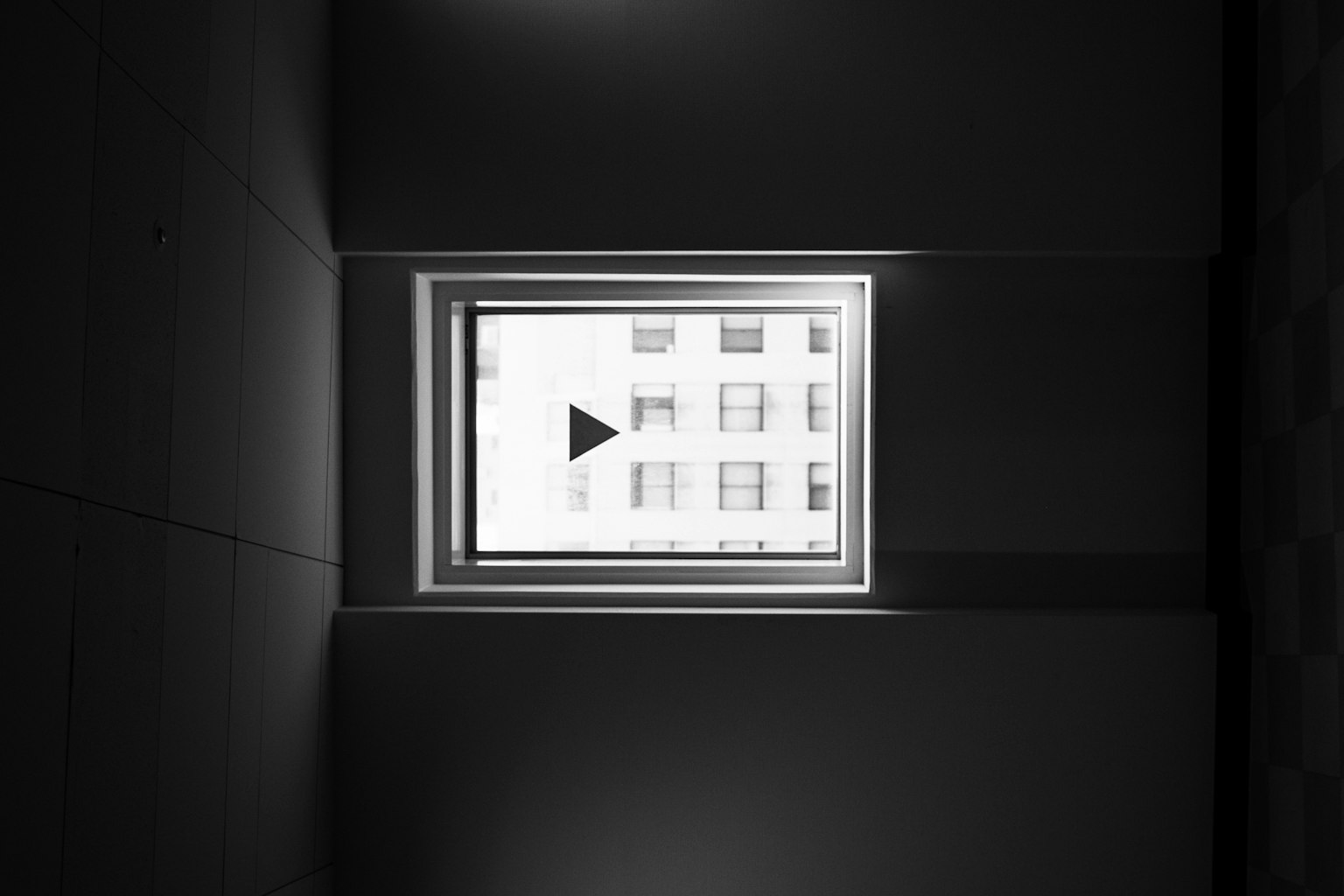 Un'immagine in bianco e nero che mostra una finestra che riflette un edificio esterno