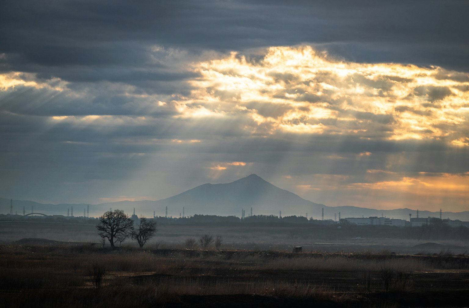 Landscape under cloudy sky with silhouette of distant mountain
