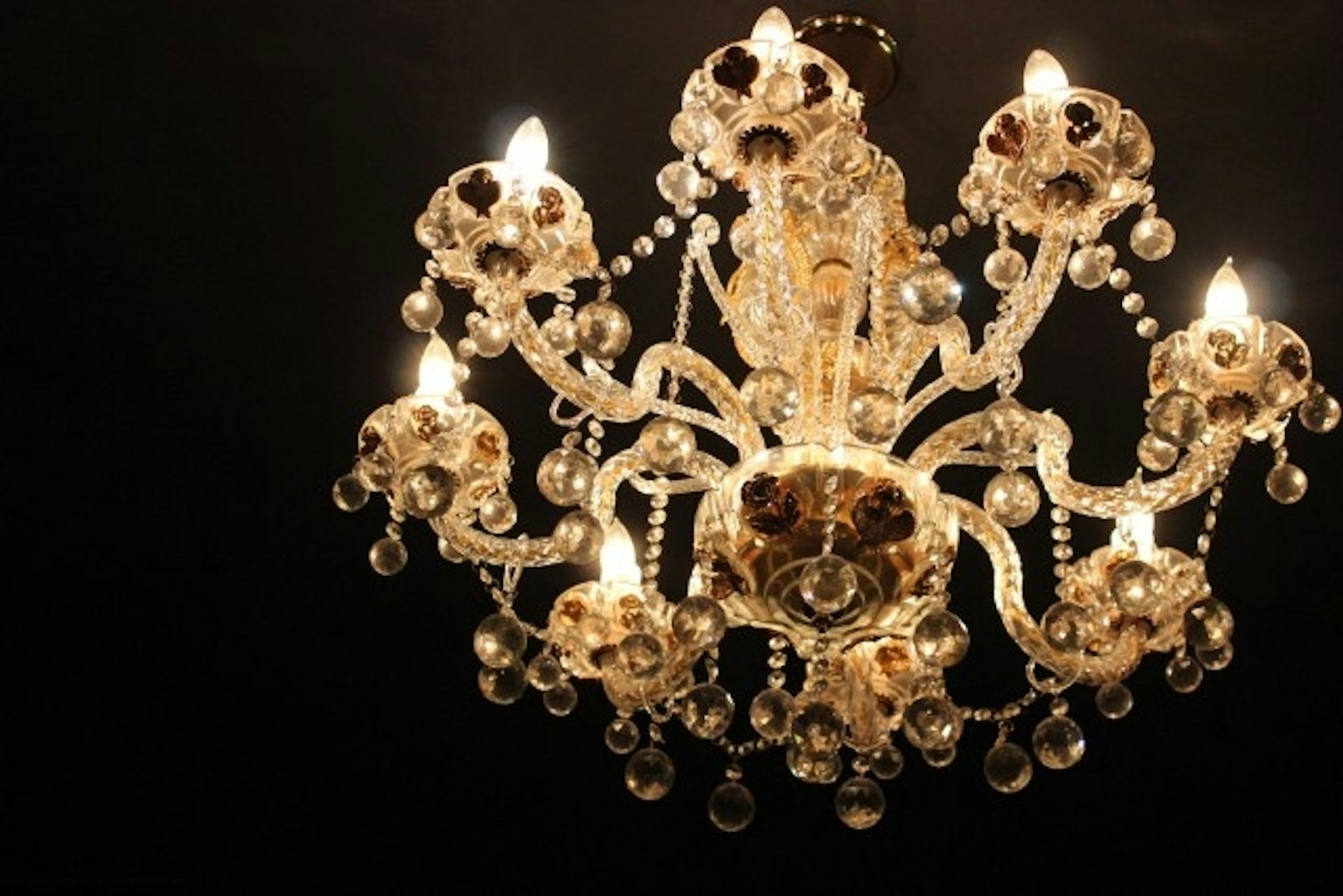 Eleganter Kronleuchter mit leuchtenden Lichtern vor schwarzem Hintergrund