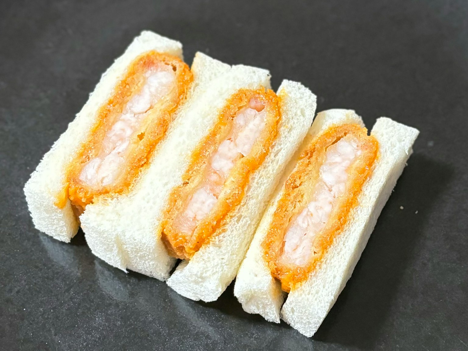 Hình ảnh ba bánh mì tôm chiên trên đĩa đen