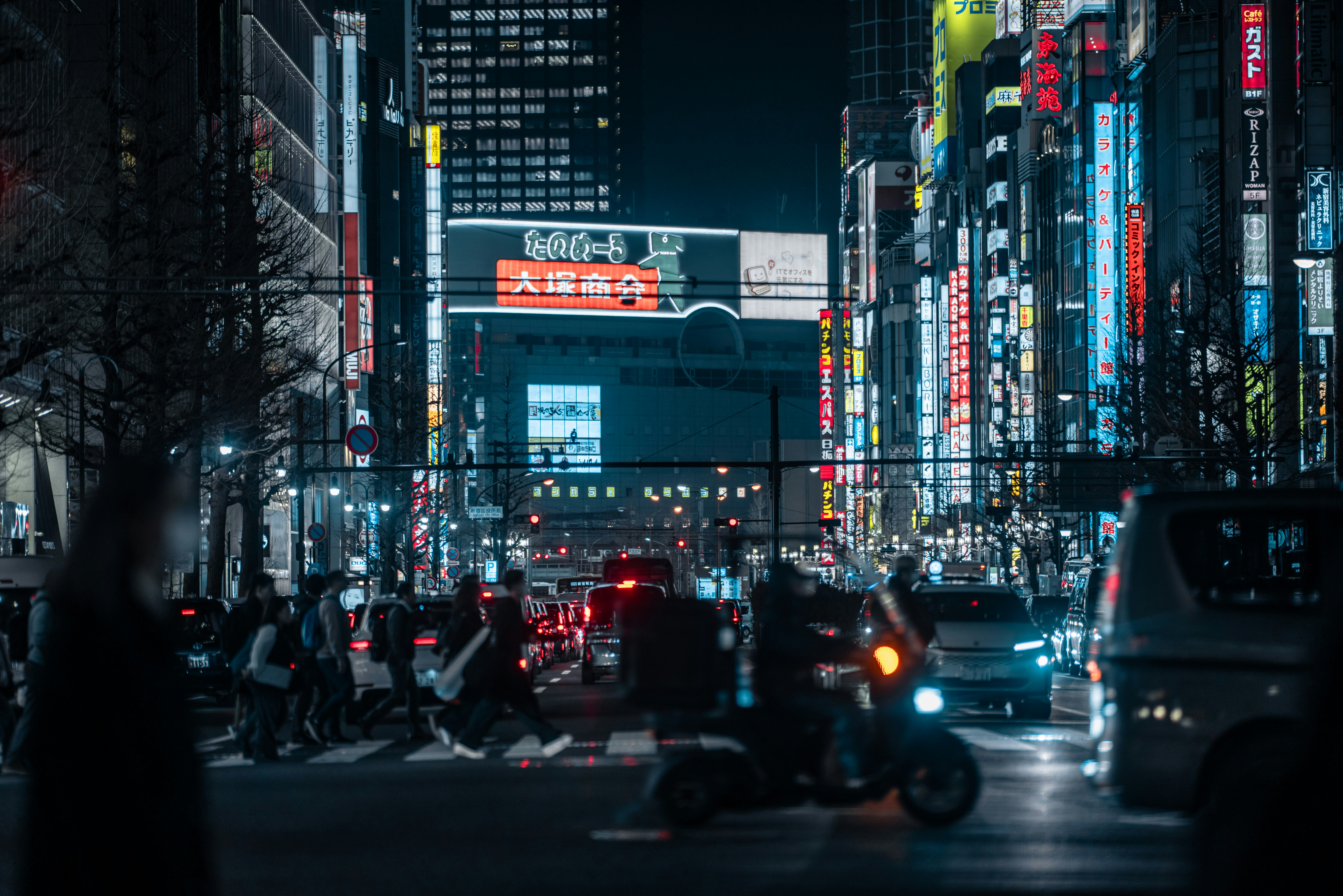 夜の繁華街を走る車とネオン看板のある大通り