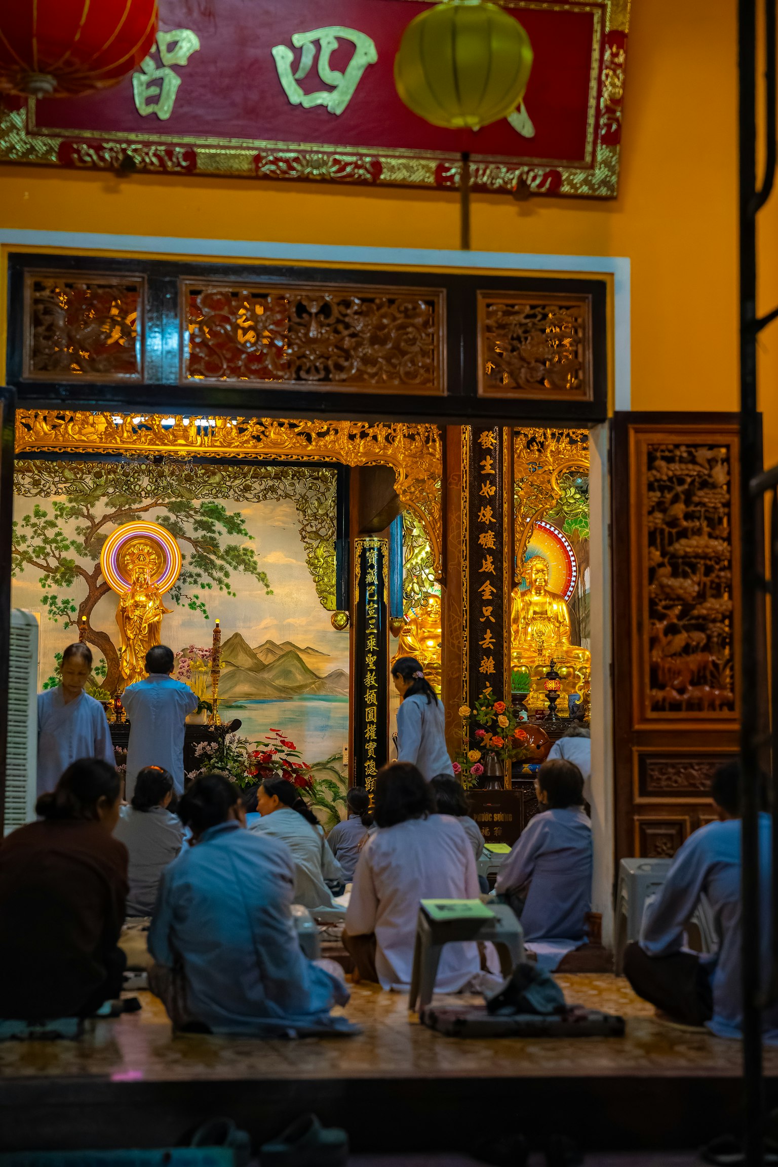 Interior of a temple with worshippers seated in front of a Buddha statue