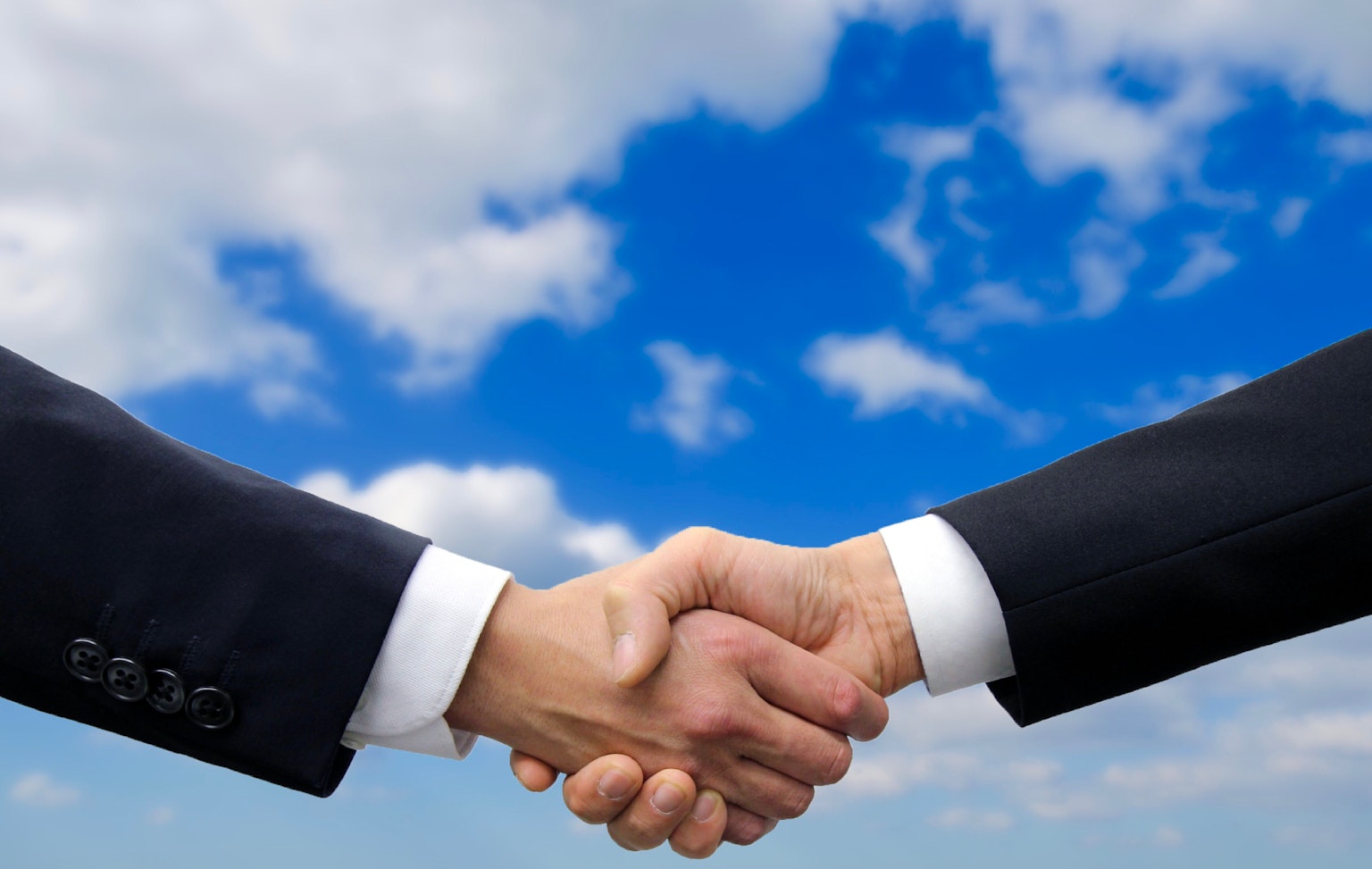 Hombres de negocios dándose la mano bajo un cielo azul