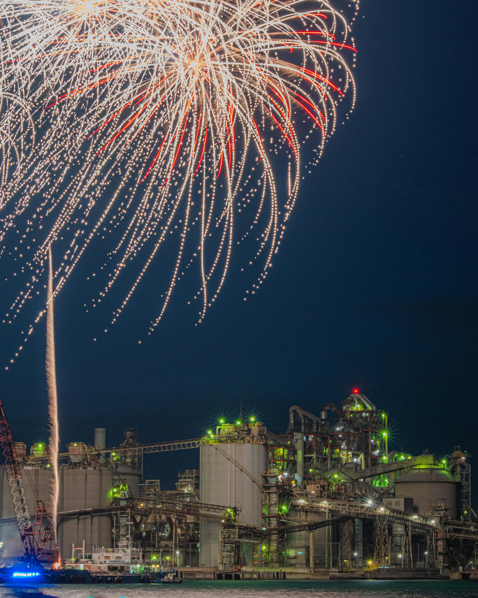 Espectáculo de fuegos artificiales sobre una instalación industrial de noche