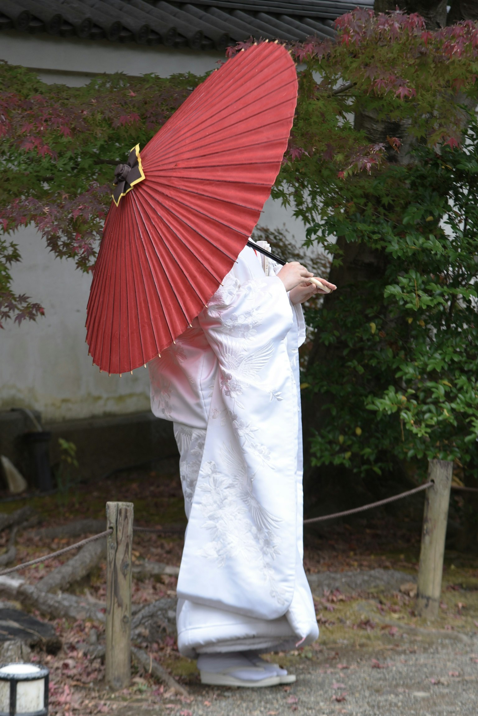 Person im weißen Kimono mit einem roten Regenschirm