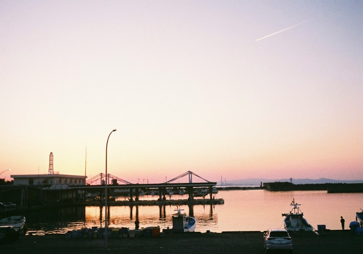 Scène de coucher de soleil paisible sur un port avec des bateaux amarrés et une eau calme