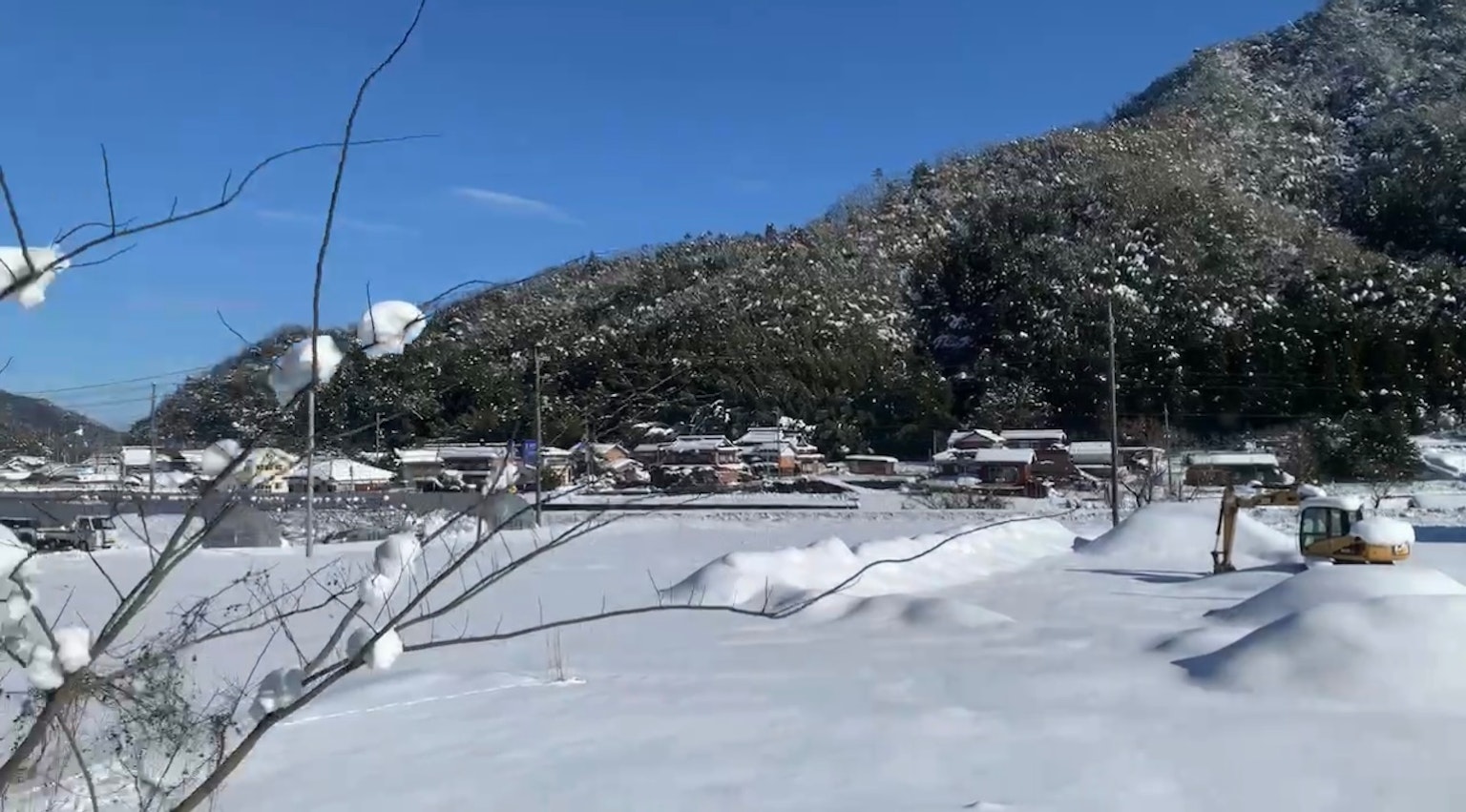 被雪覆盖的风景和蔚蓝天空下的山村