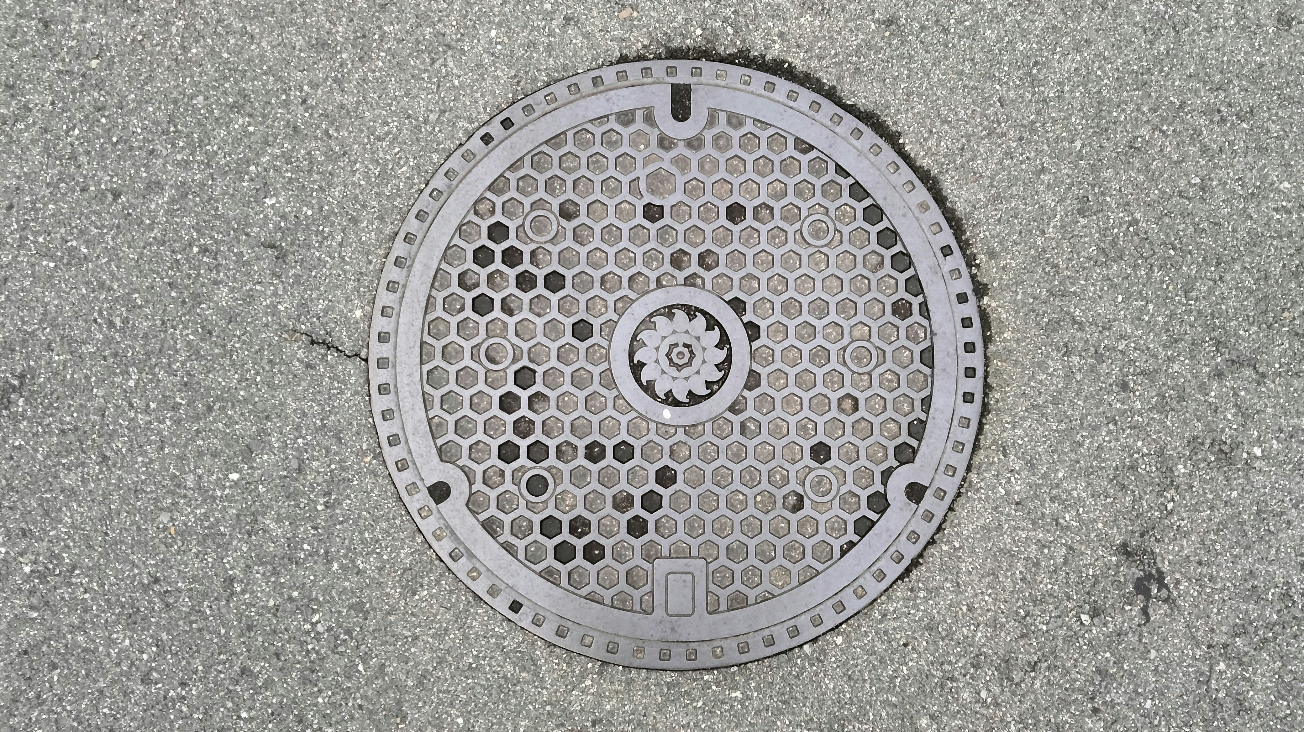primer plano de una tapa de alcantarilla circular con patrón de rejilla