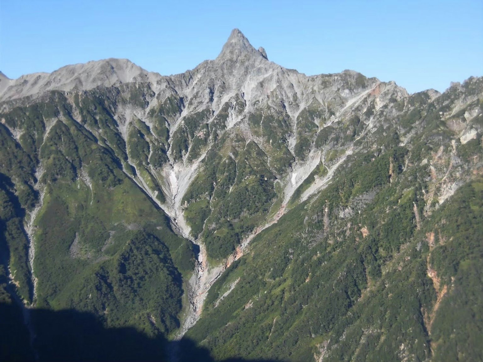 Paisaje montañoso escénico con valles verdes y un pico puntiagudo
