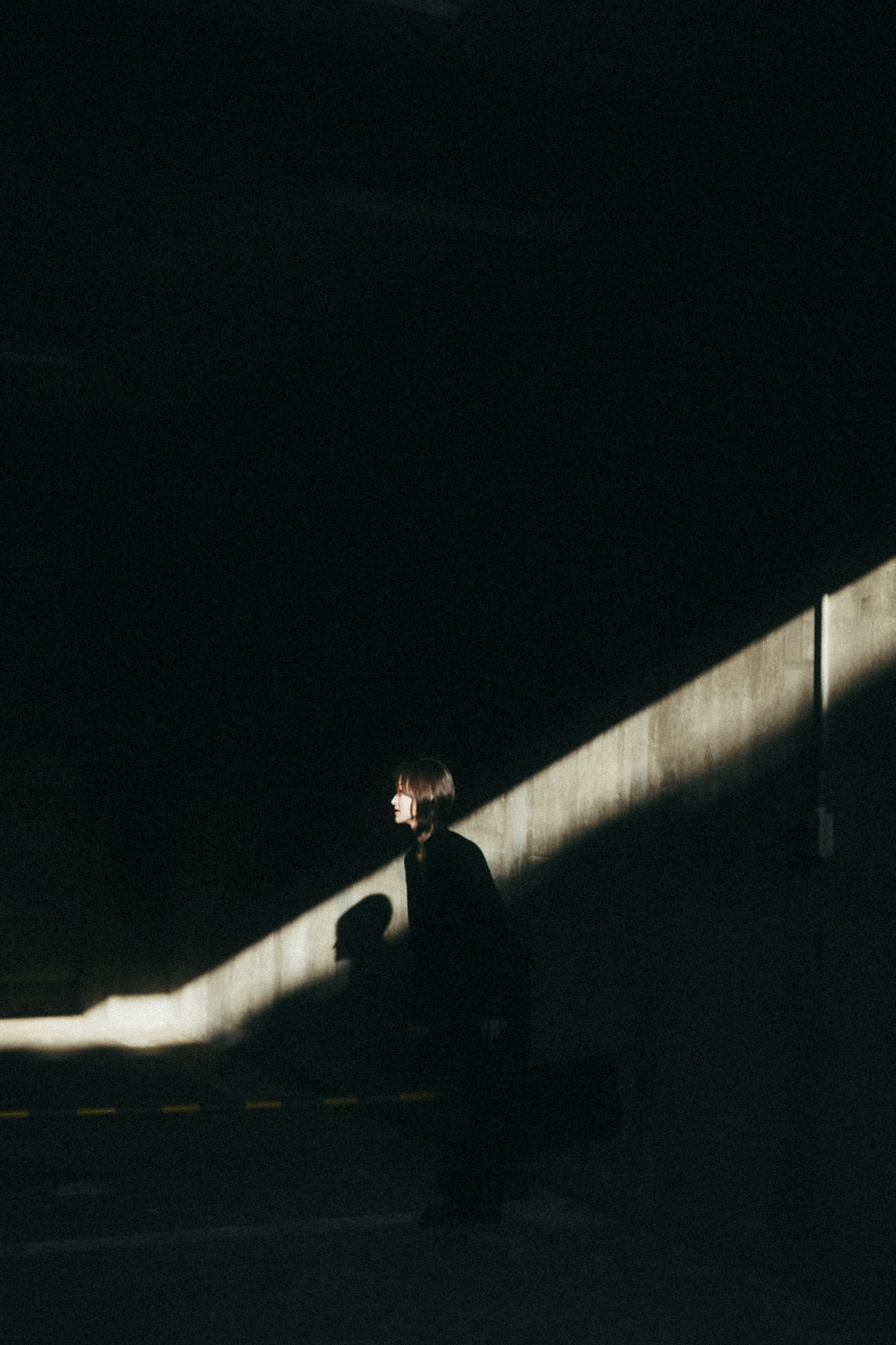 Une personne se tenant contre un fond sombre avec de la lumière projetée sur le mur