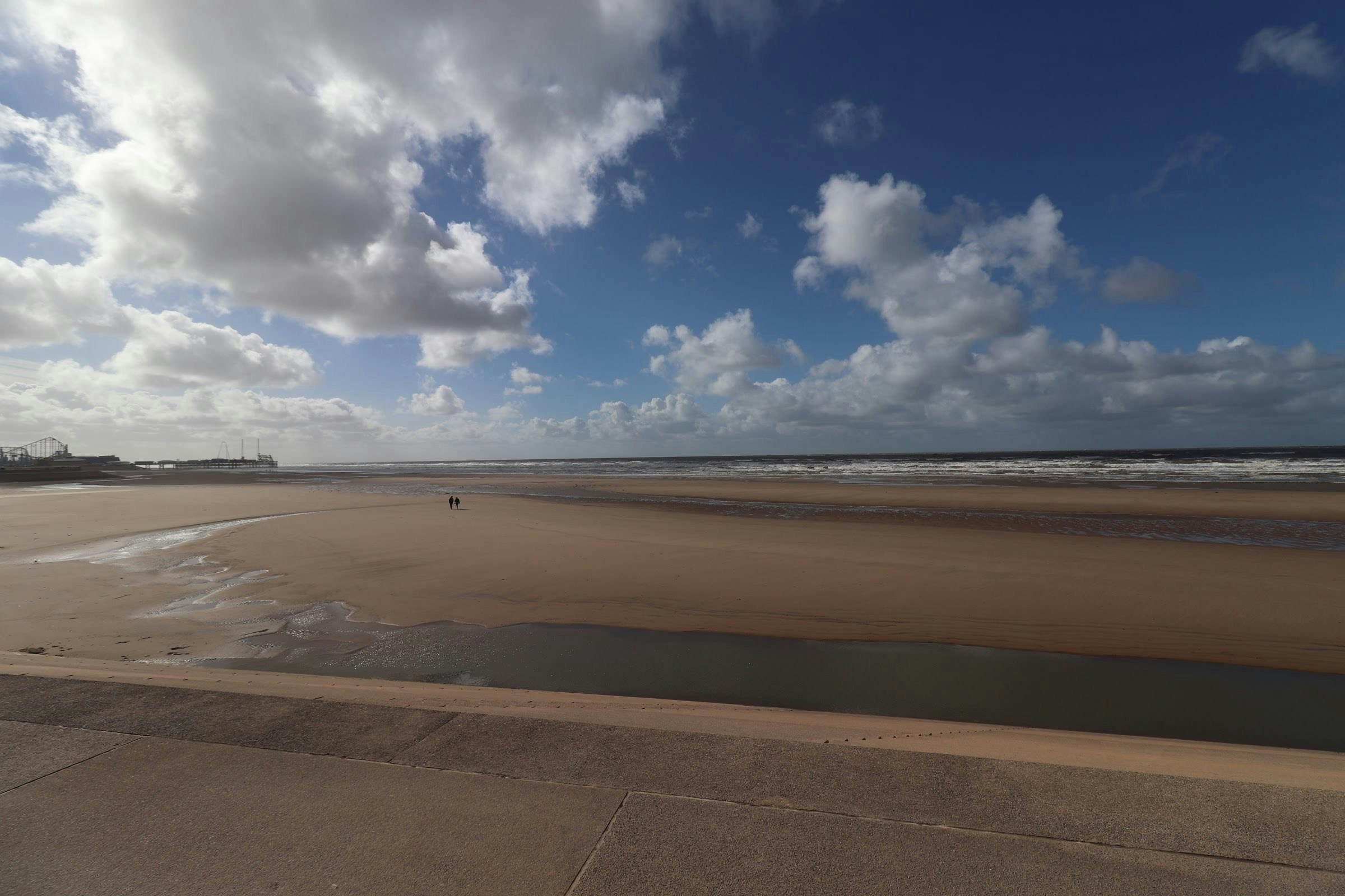 wide sandy beach and calm sea under a cloudy sky