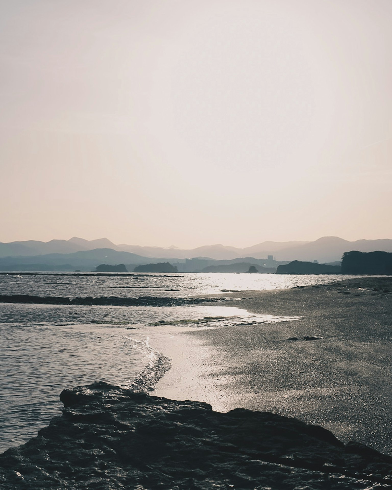 日落時寧靜的海景，背景有遙遠的山脈