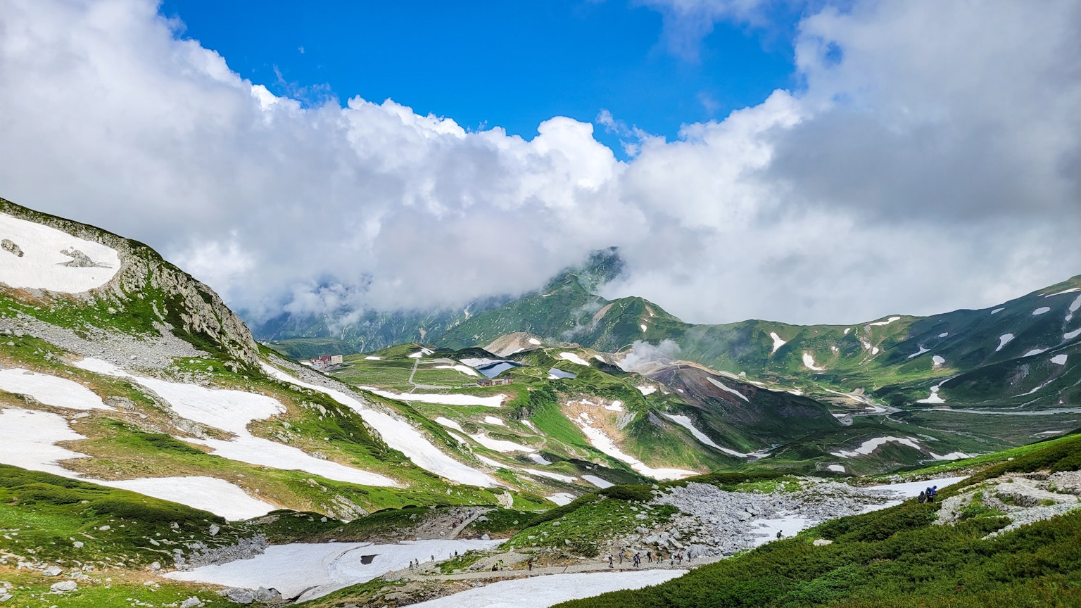 Pemandangan gunung yang indah kontras hijau dan salju langit biru dan awan