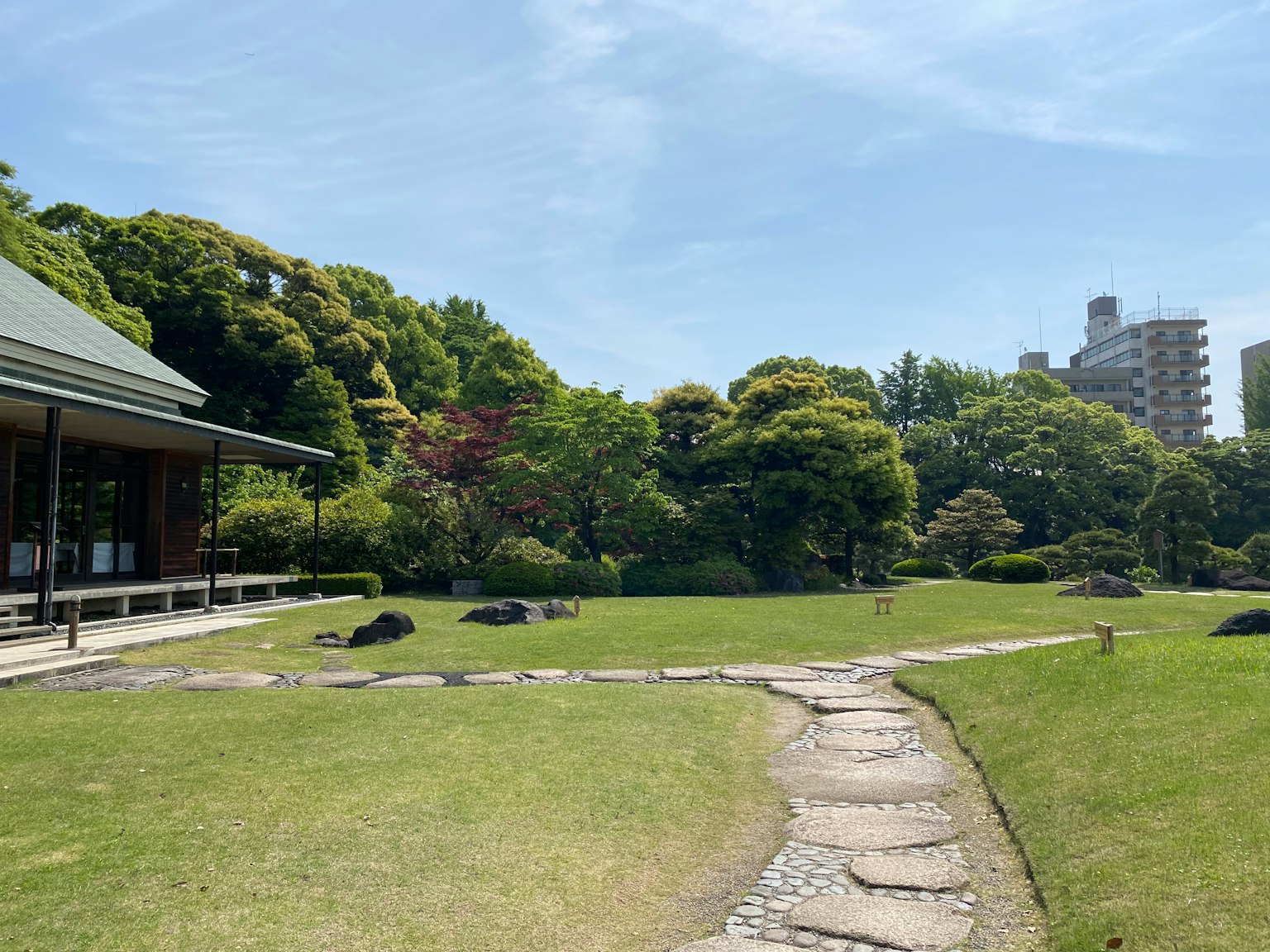 Vue d'un jardin japonais spacieux avec une végétation luxuriante et un chemin en pierre
