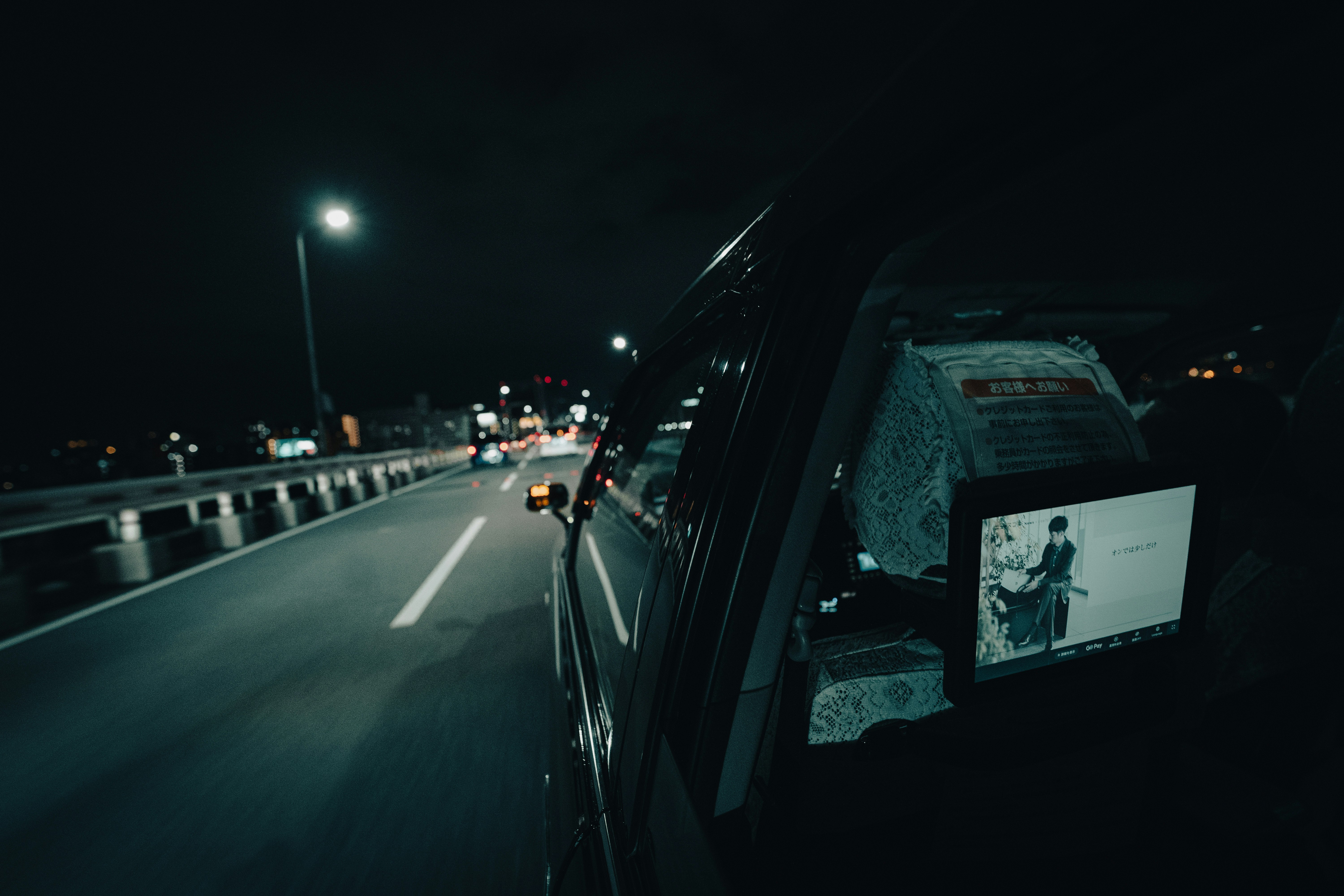 夜の高速道路でタクシーの車内モニターが光る場面