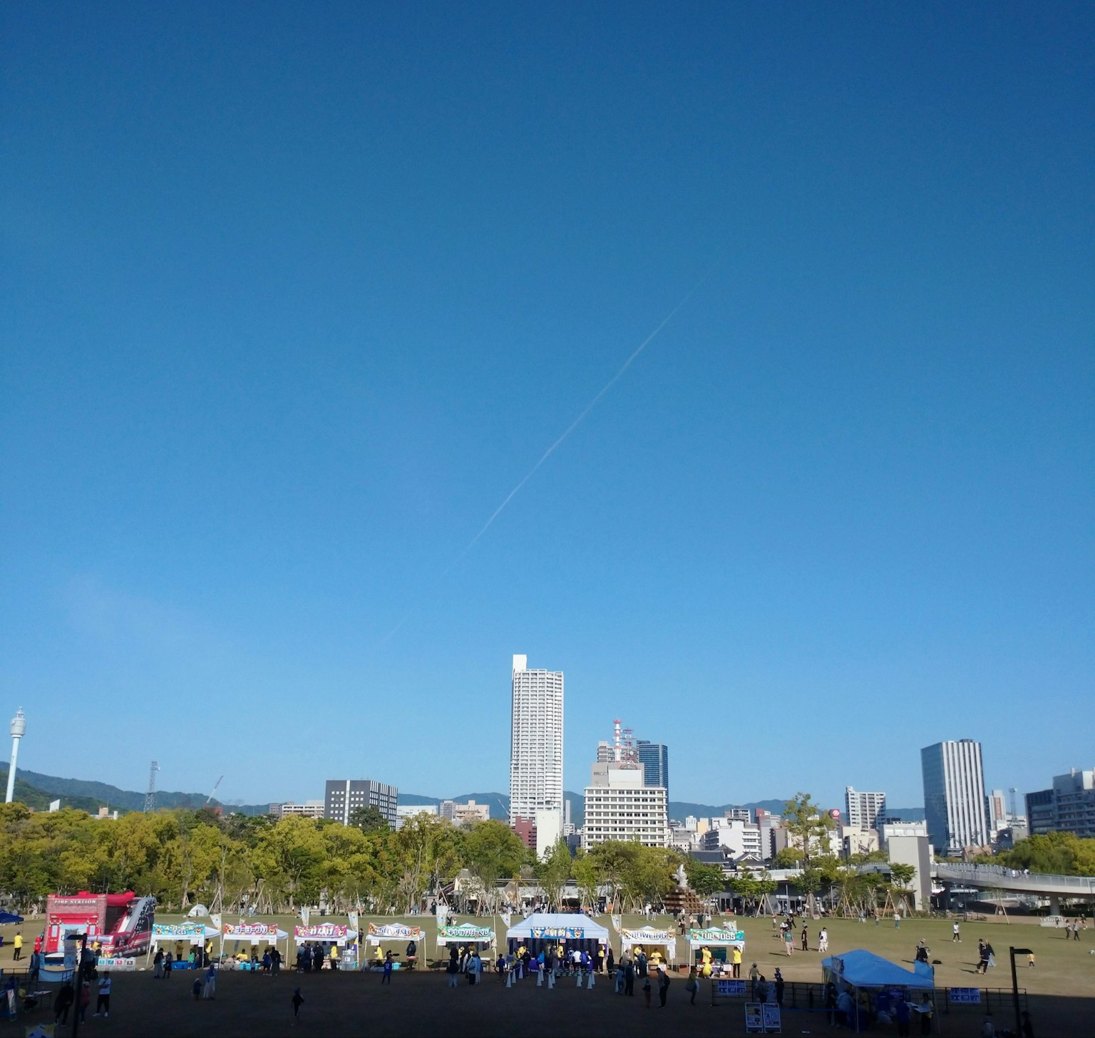 Paisaje urbano bajo un cielo azul claro con carpas de eventos al aire libre