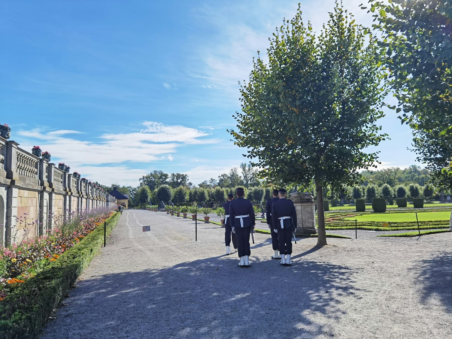 Two individuals walking in a garden with lush greenery
