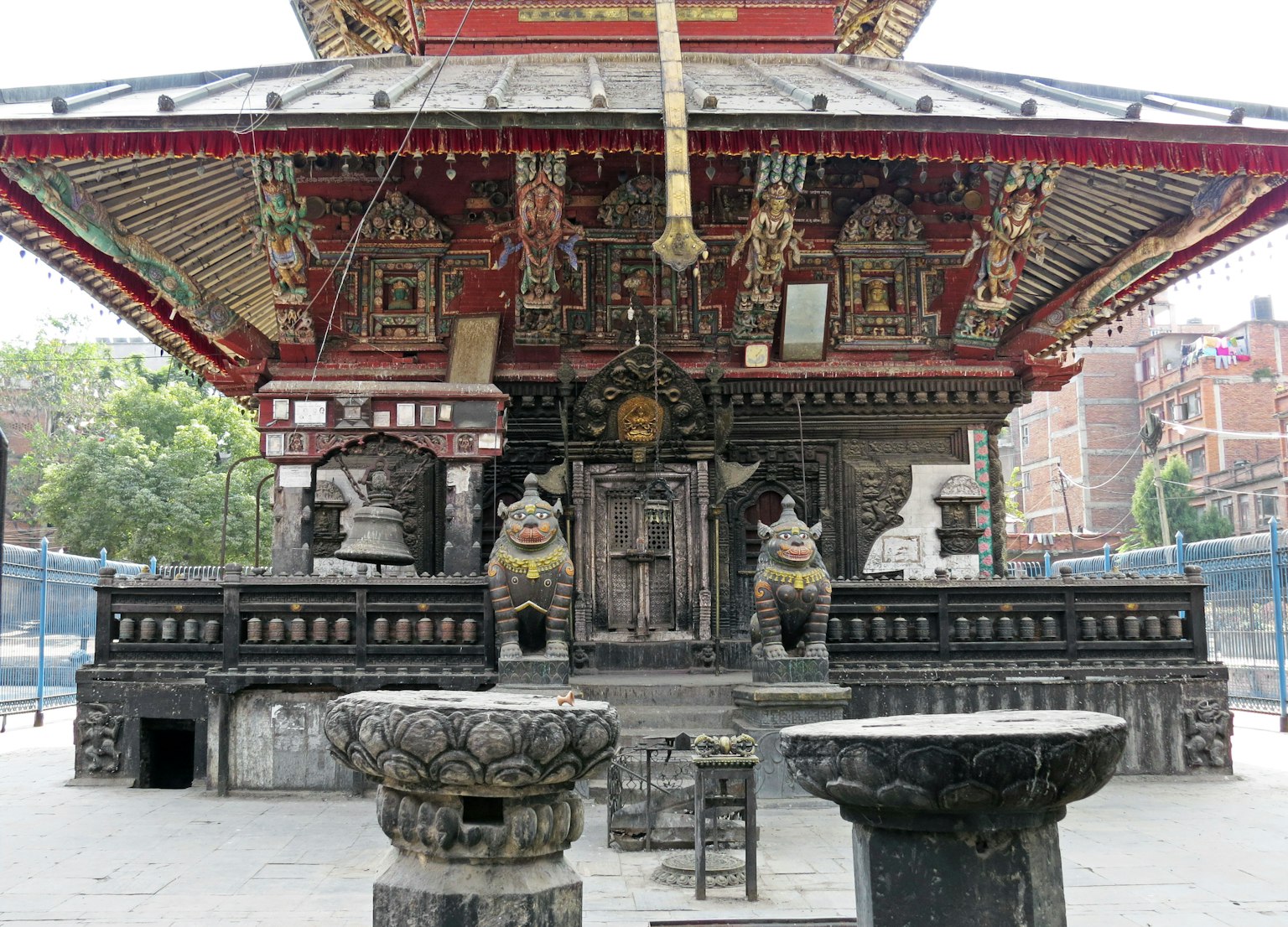 Une structure de temple ancien avec un toit décoré et des colonnes finement sculptées avec une statue de divinité centrale