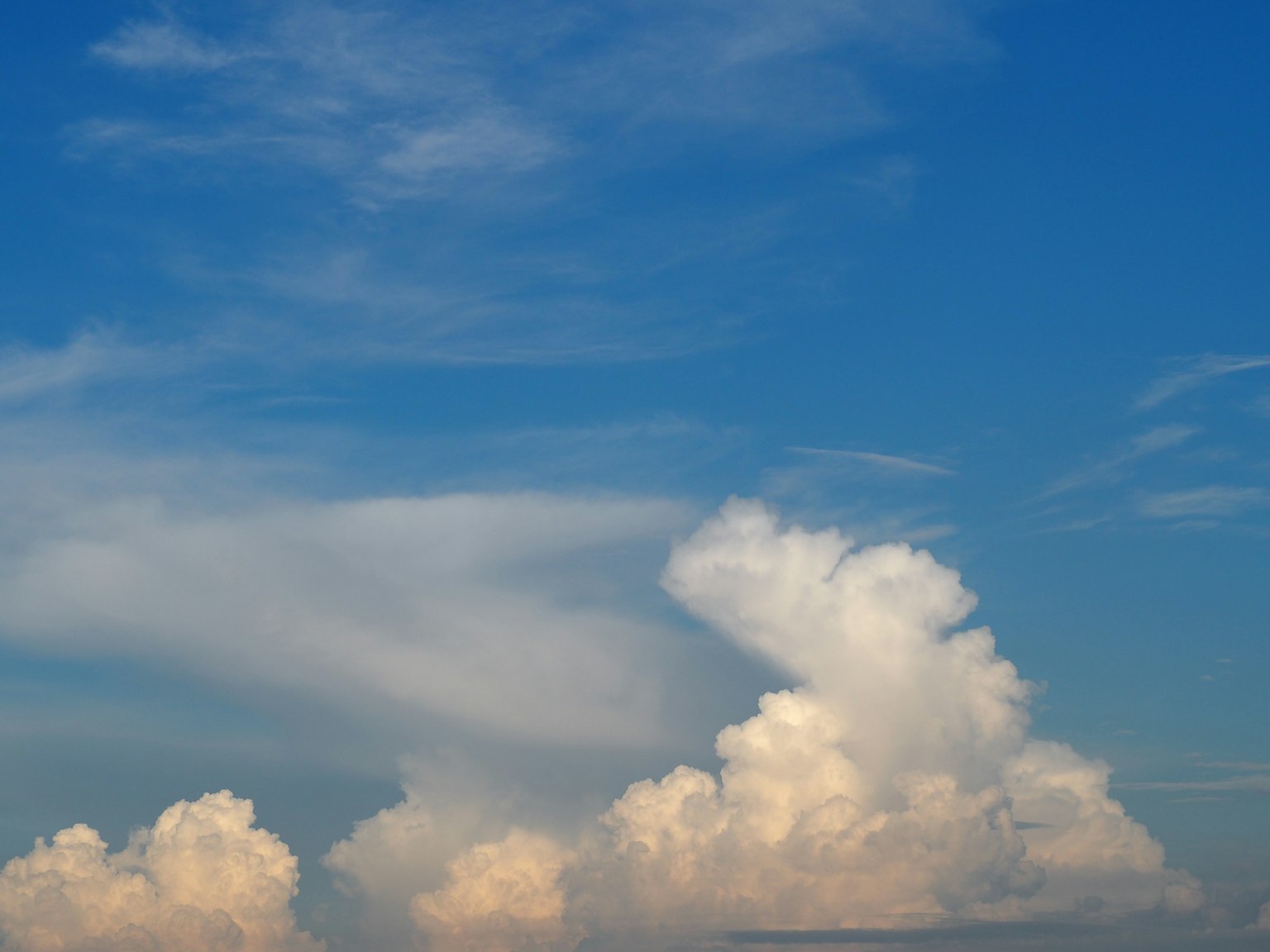 A landscape featuring white clouds against a blue sky